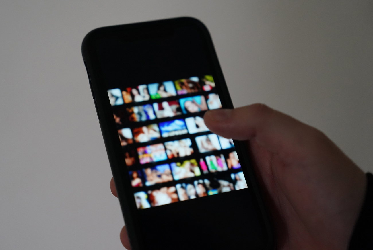 Ein Mann schaut sich auf einem Smartphone eine Porno-Internetseite an (gestellte Szene).