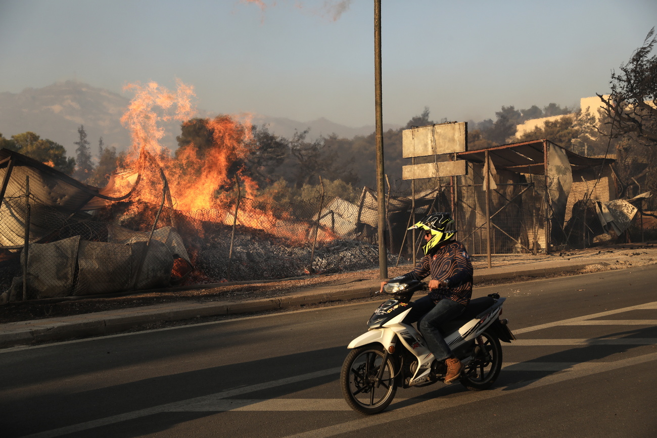 scooter passa accanto a edificio in fiamme