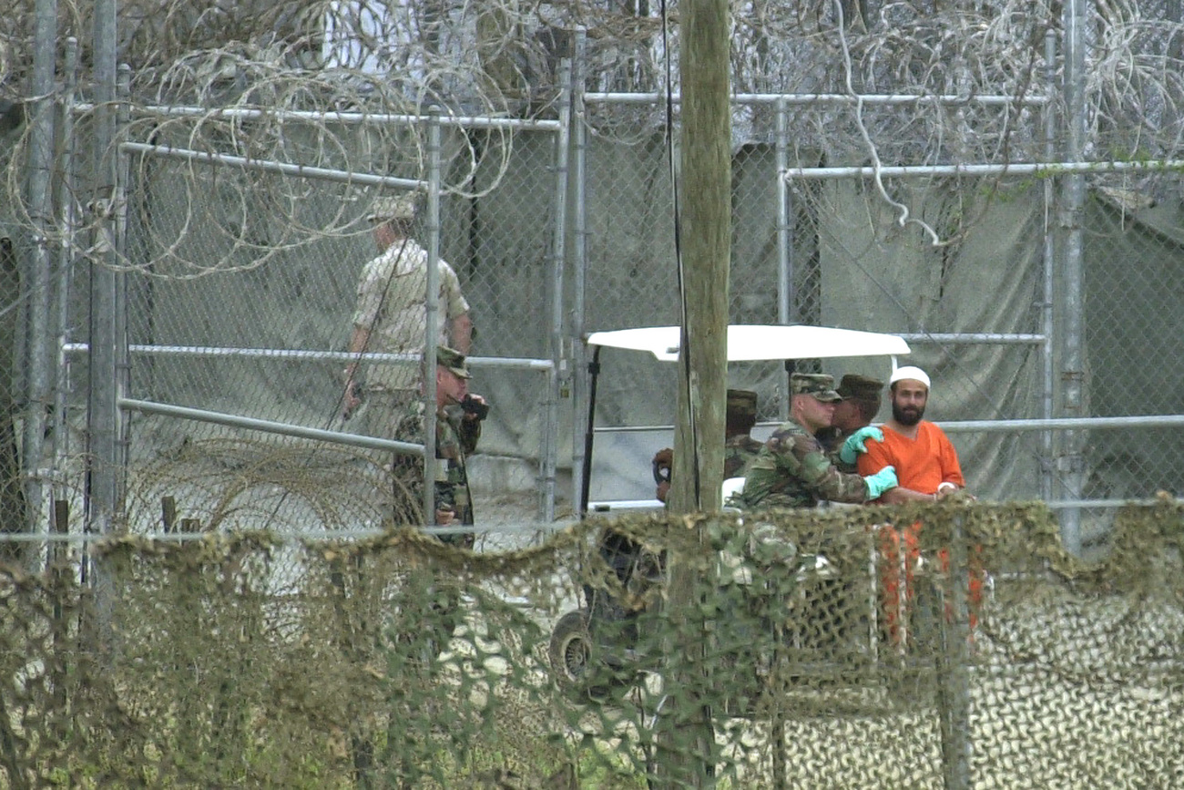 Ein Häftling in einem orangefarbenen Schutzanzug wird am Mittwoch, 27. März 2002, in das Camp X-Ray auf dem US-Marinestützpunkt in Guantanamo Bay, Kuba, gebracht.