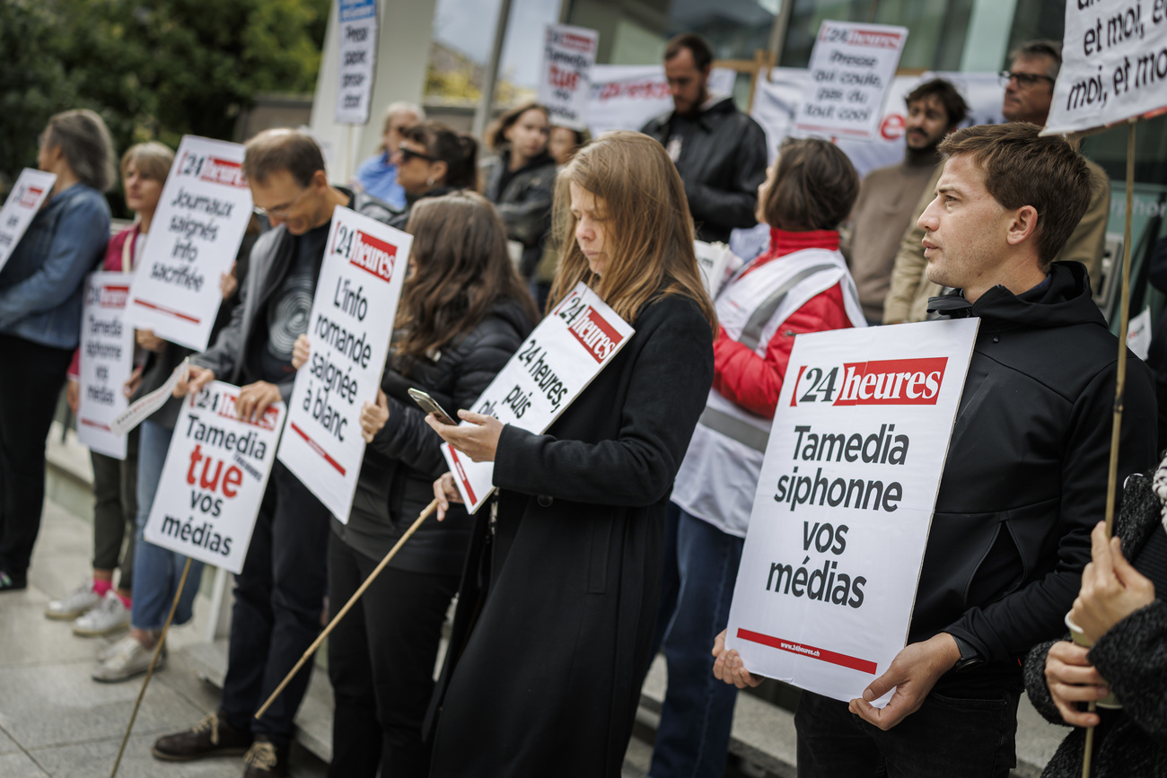 Journalisten und Angestellte von Tamedia Suisse romande hielten während einer Arbeitsniederlegung vor dem Tour Edipresse in Lausanne am Donnerstag, den 12. September 2024, Plakate hoch, um gegen eine geplante Umstrukturierung zu protestieren,