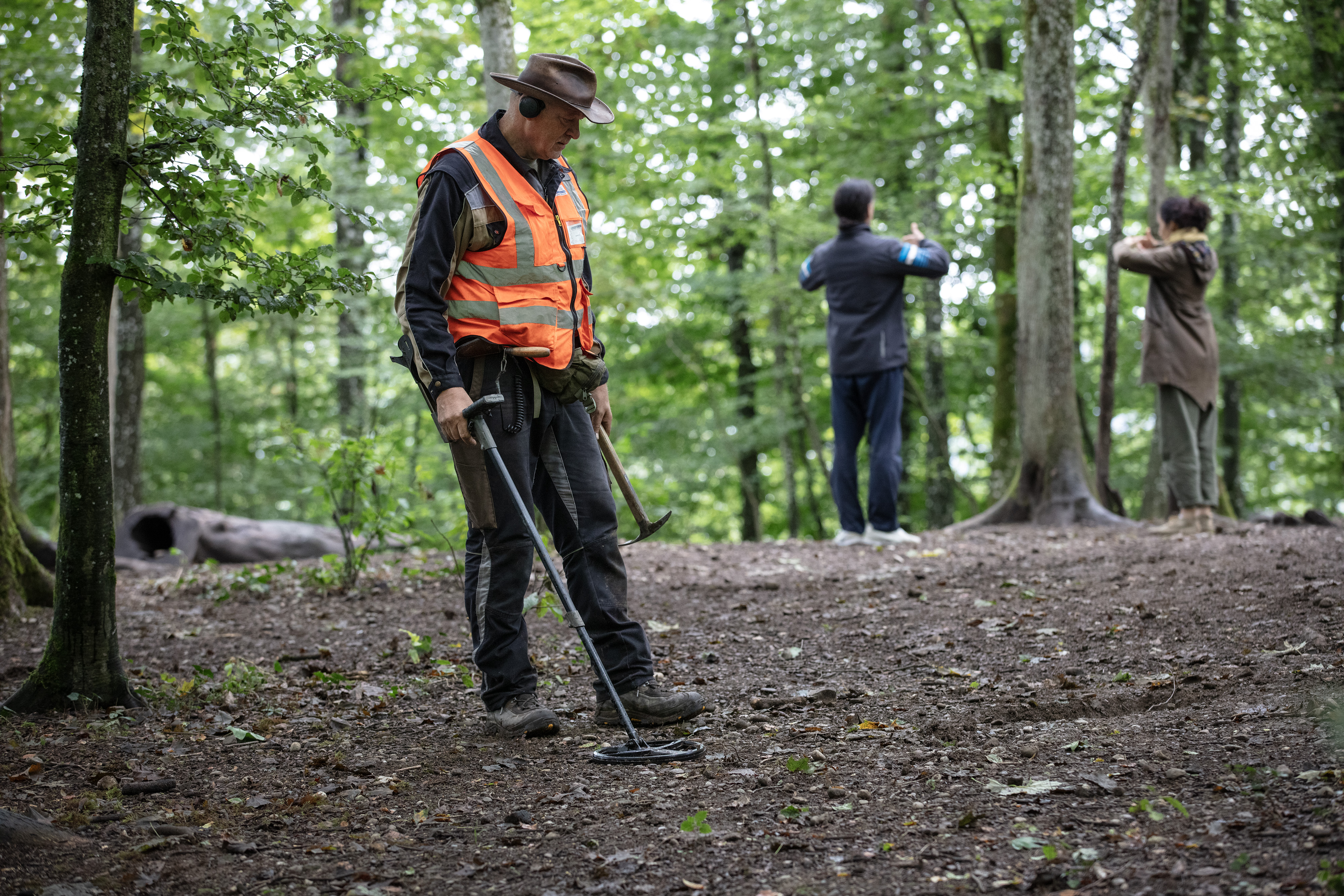 Ein Mann im Wald, im Hintergrund üben zwei Personen Tai-Chi