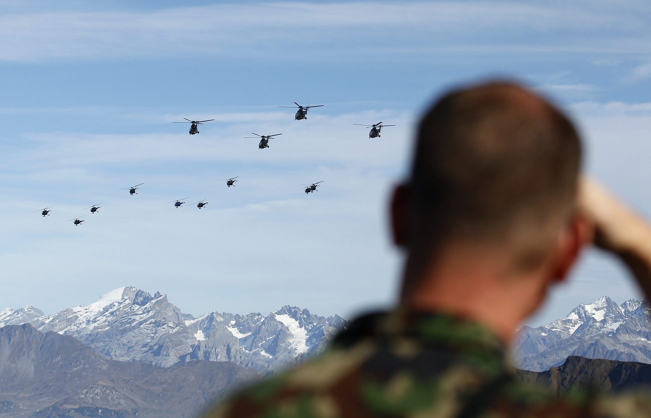 Ein Mitglied der Schweizer Armee beobachtet Helikopter am Himmel