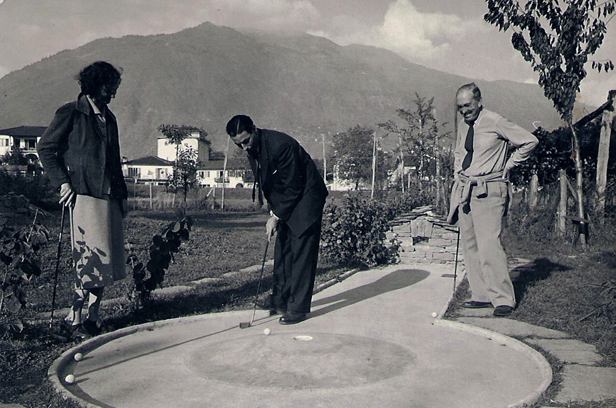 Foto em preto e branco de pessoas jogando minigolfe