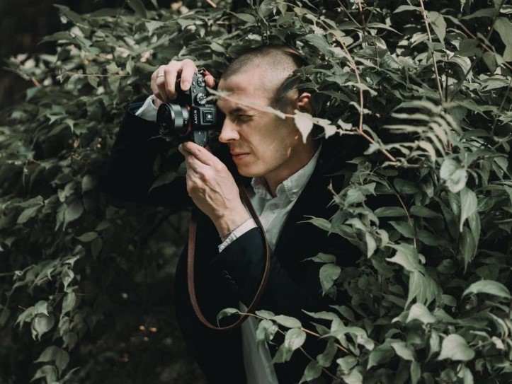 Um homem fotografando escondido no arbursto