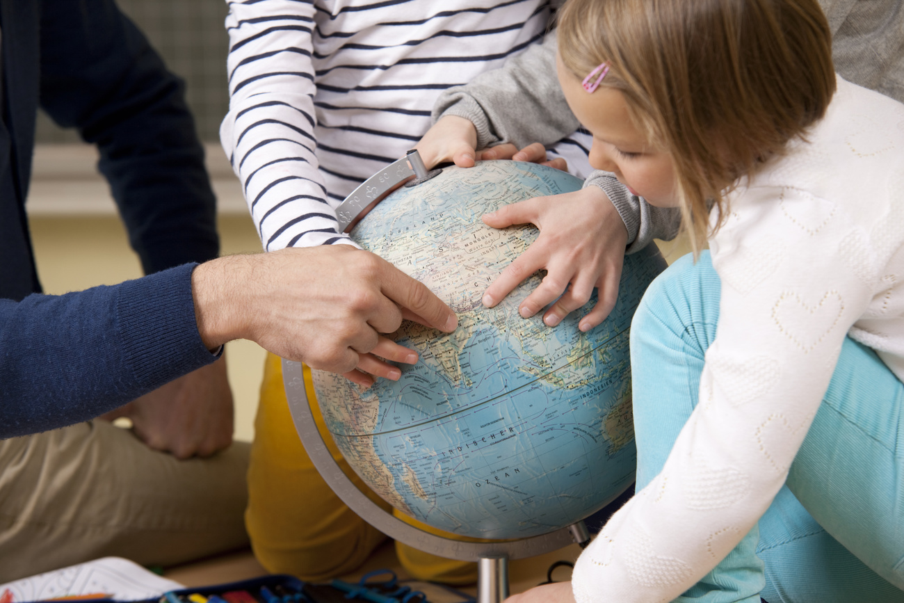 Three people point their fingers at a globe