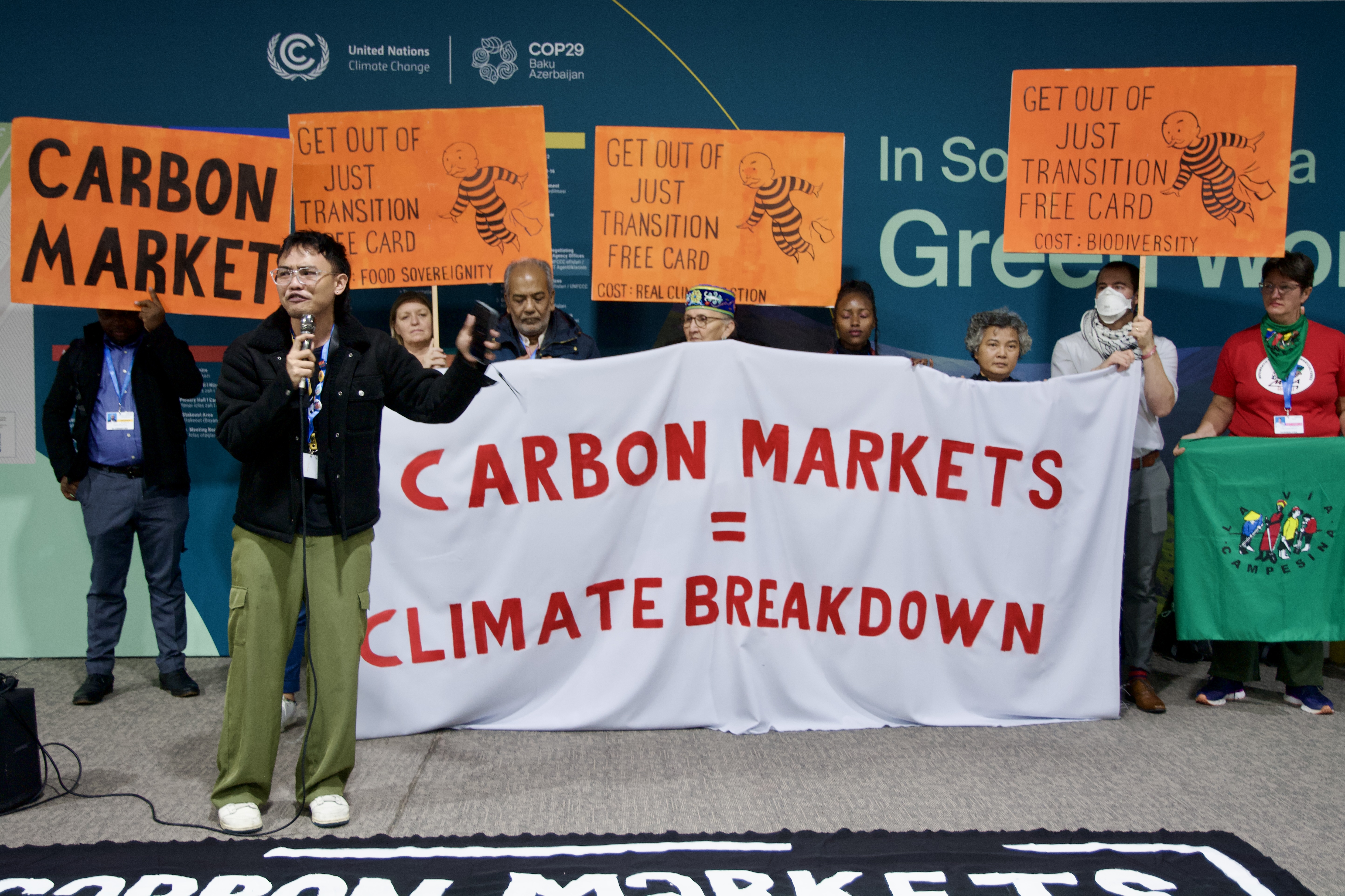 gente mostra cartelloni che denunciano i mercati del carbonio