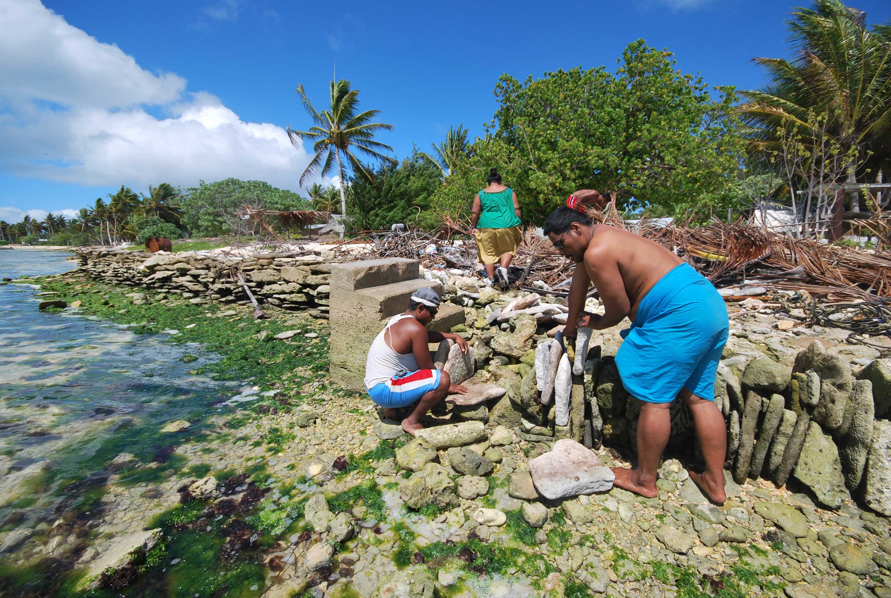 Residents of Kiritimati, a Pacific atoll, build a stone seawall to rising sea levels resulting from the climate crisis.