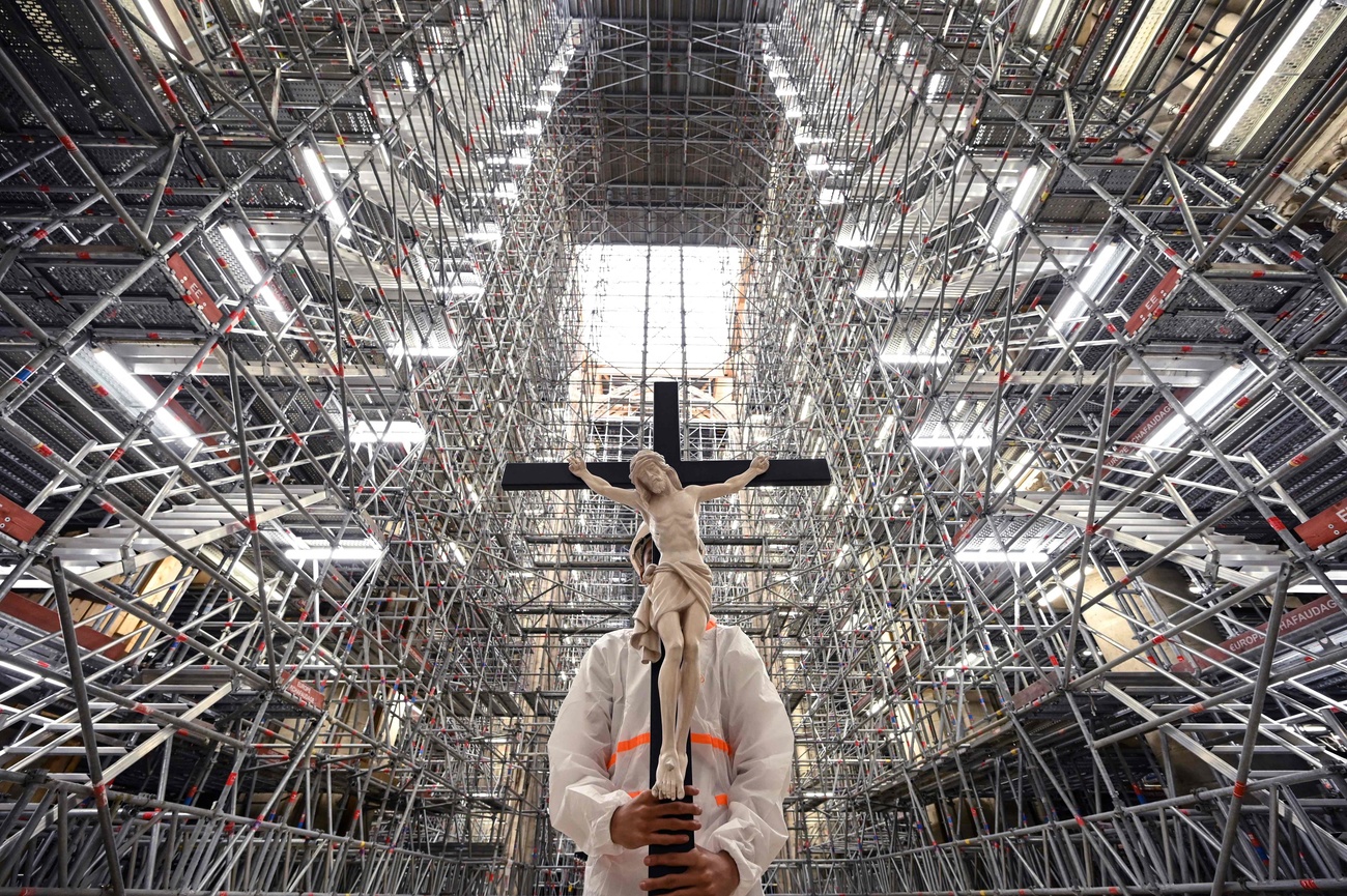 Un fidèle catholique tient un crucifix lors d'une prière effectuée par des prélats dans la cathédrale Notre-Dame, marquant le troisième anniversaire, en 2022, de l'incendie qui a partiellement détruit la cathédrale.