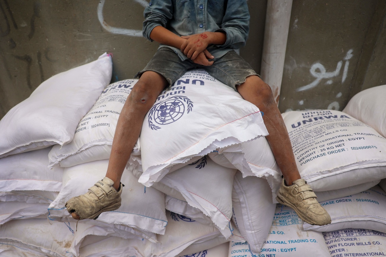 Child sitting on top of bags of flour donated to UNRWA