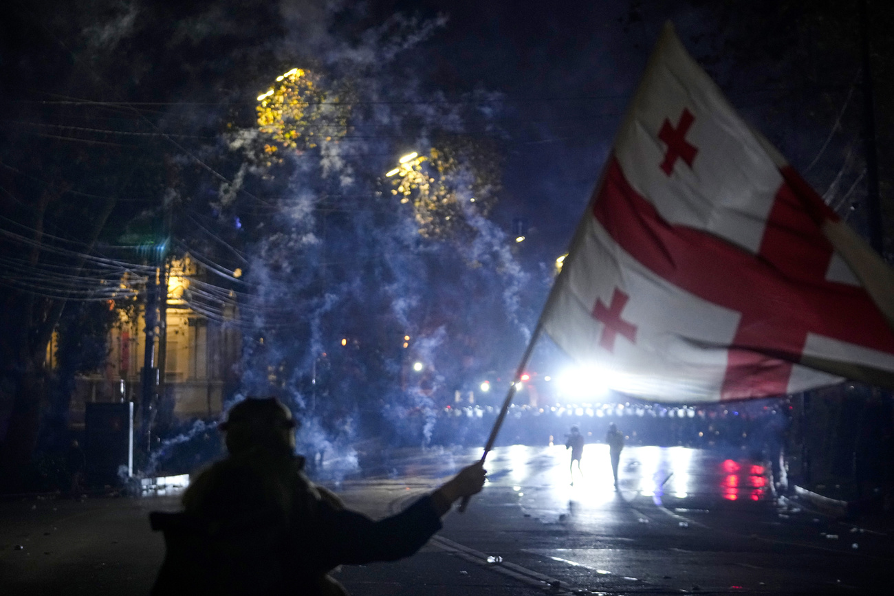 A demonstrator waves a Georgian flag during a protest against the governments' decision to suspend negotiations on joining the European Union in Tbilisi, Georgia, early Saturday, Dec. 7, 2024. (AP Photo/Pavel Bednyakov)