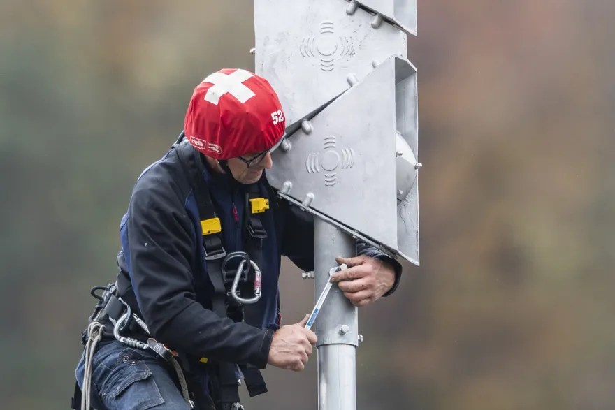 Ein Mann mit Helm auf dem Kopf hantiert an einer Sirene herum