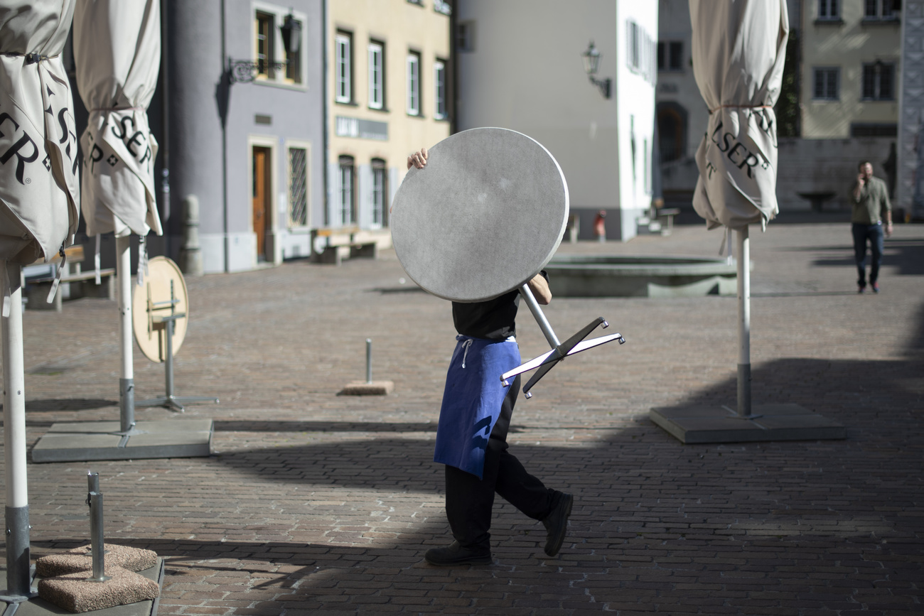 An employee carries a table into Café Arcas on Monday, 16 March 2020, in Chur. The Graubünden government had decided to close shops and restaurants due to the coronavirus.