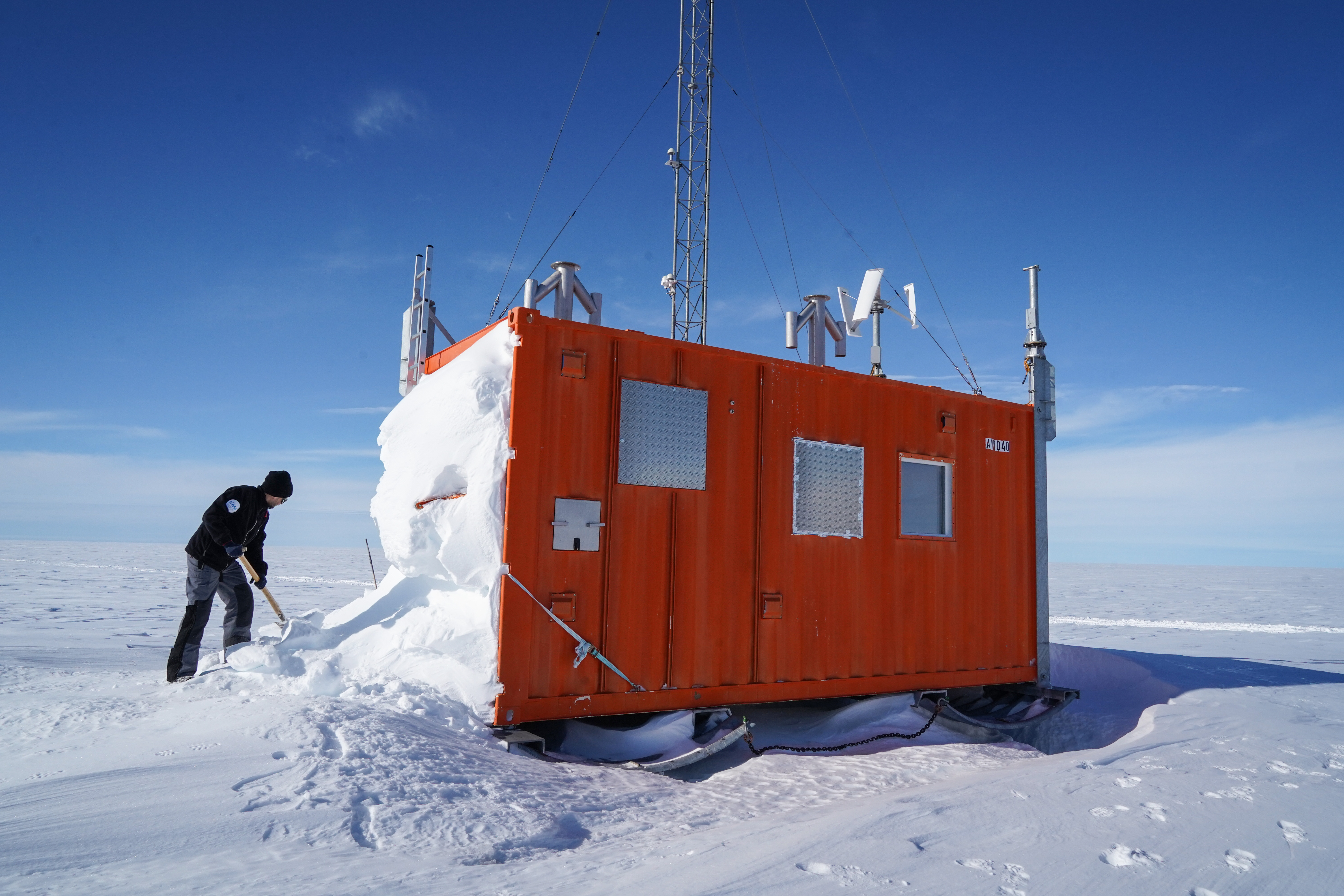 Ein Mann schaufelt einen Kontainer vom Schnee frei