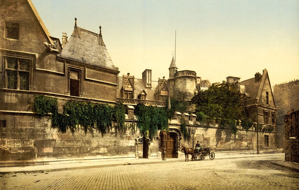 Foto antiga colorida mostrando um prédio e pessoas