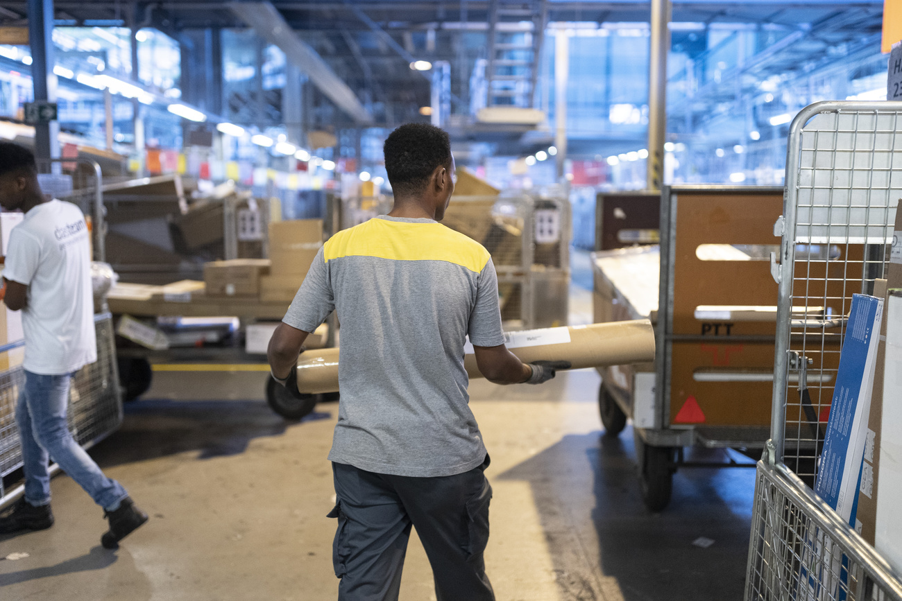 Persona migrante trabajando en correos suizo.