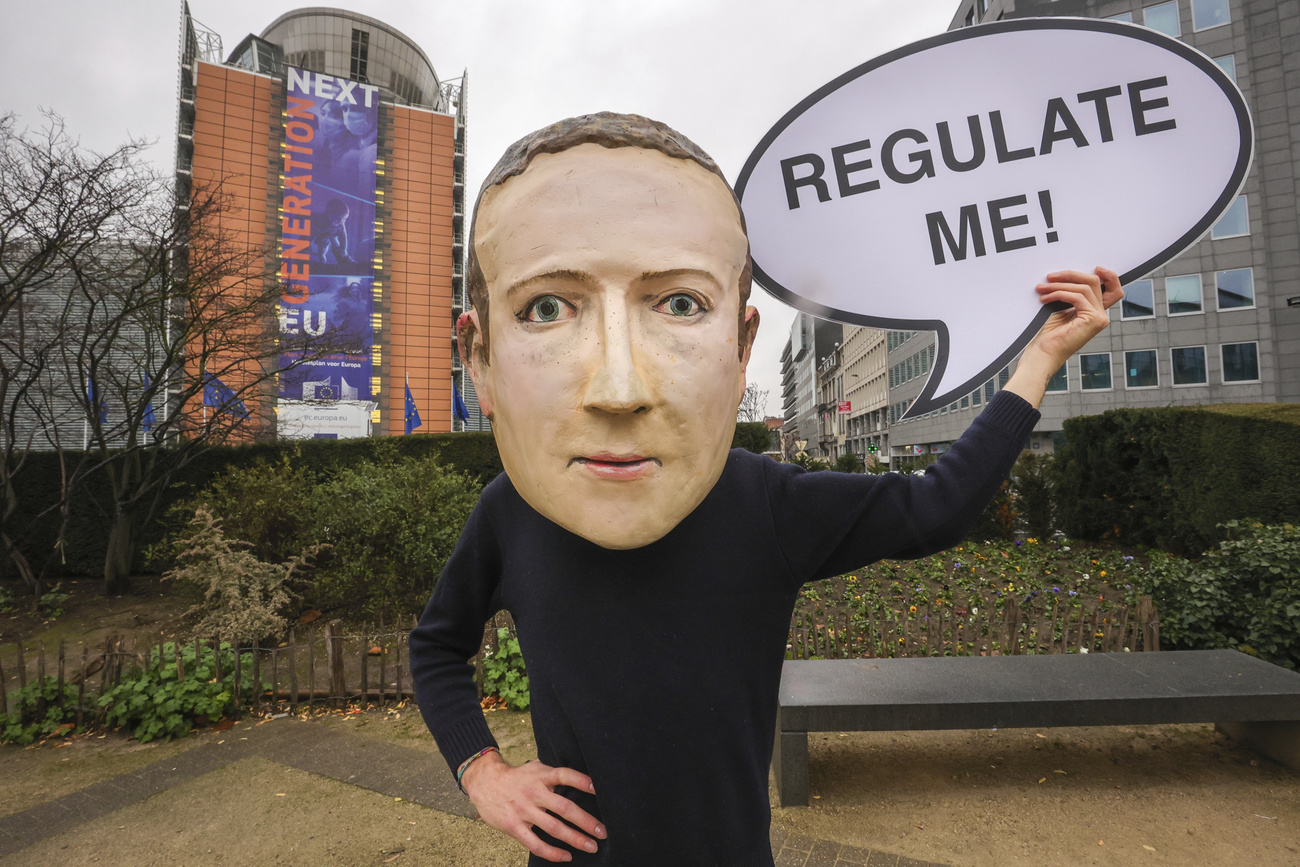 A campaigner from the global citizens movement Avaaz wearing a mask of Facebook CEO Mark Zuckerberg holds a sign reading "Regulate me", outside the European Commission on the day the Digital Services Act was published, on December 15, 2020 in Brussels.