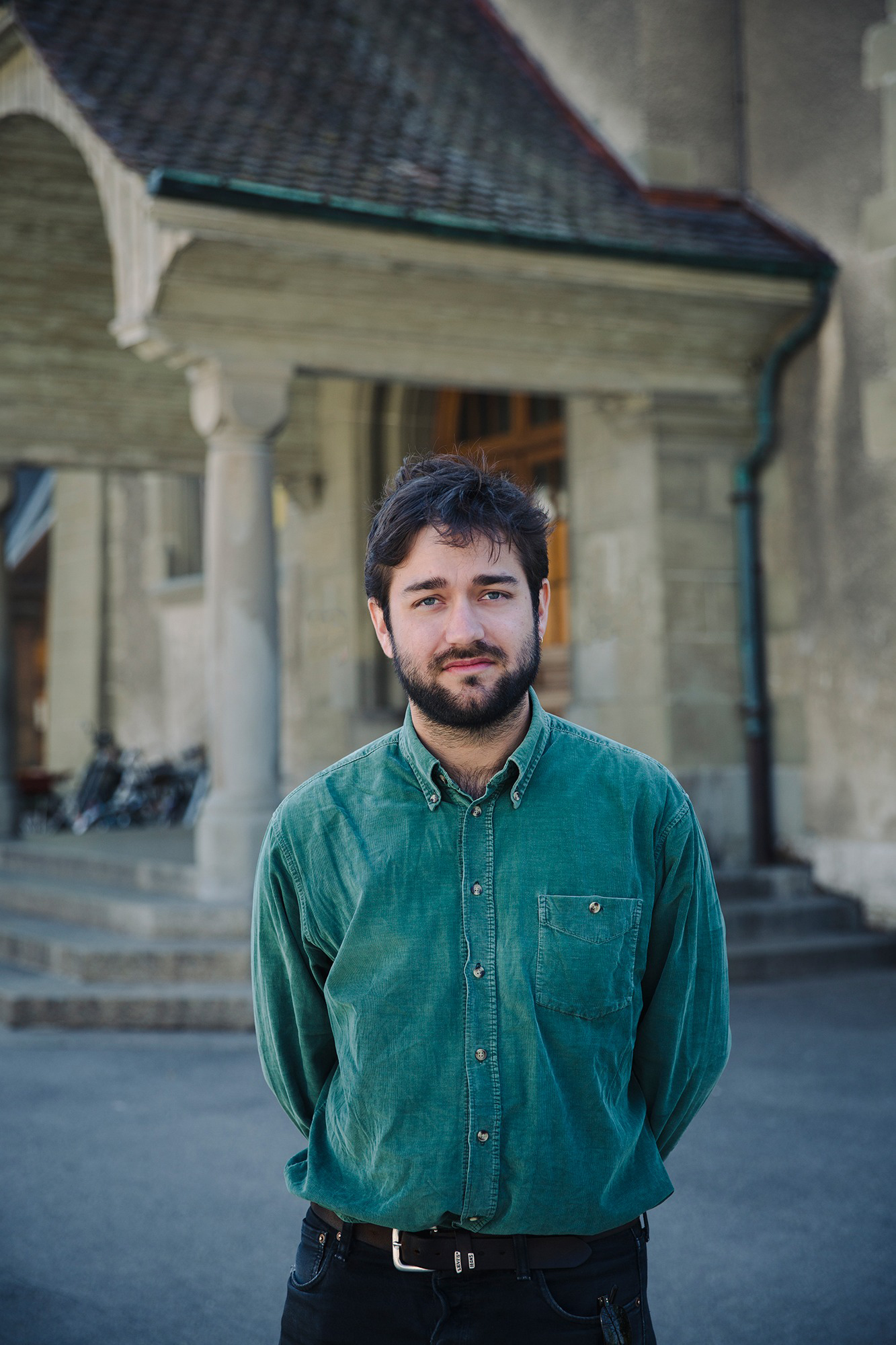 Mateo Ybarra stands outdoors, with a historic building and bicycles in the background.
