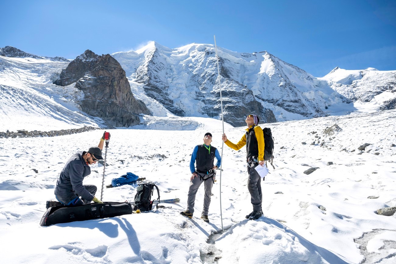 ricercatori misurano lo spessore di un ghiacciaio con delle aste graduate