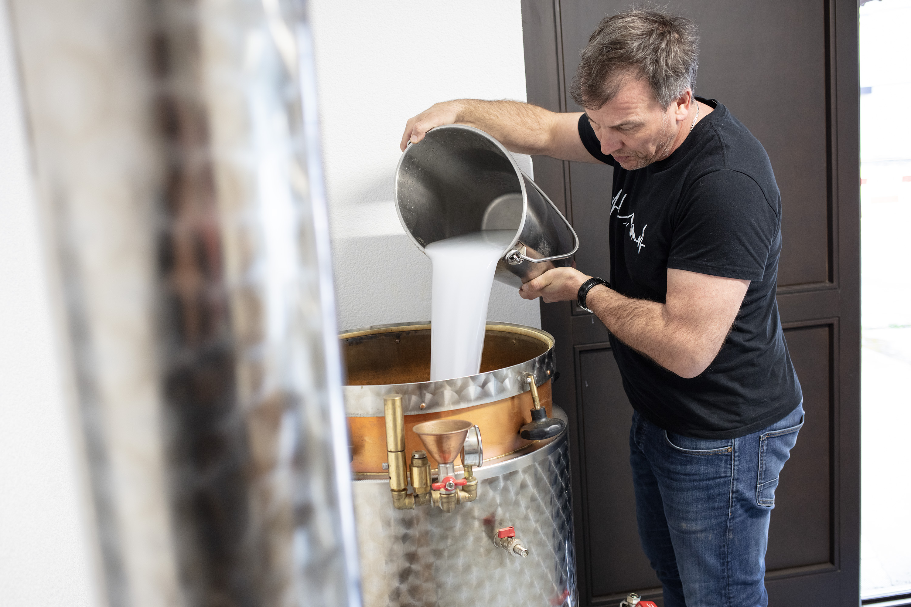 uomo versa un secchio da cui esce un liquido bianco