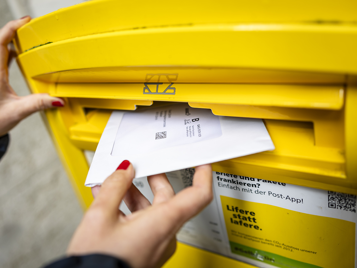 persona imbuca lettera in cassetta gialal della Posta