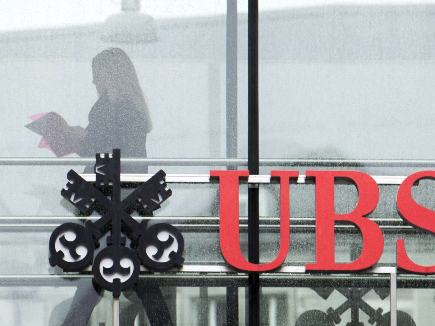 riflesso di donna in una vetrata con il logo ubs