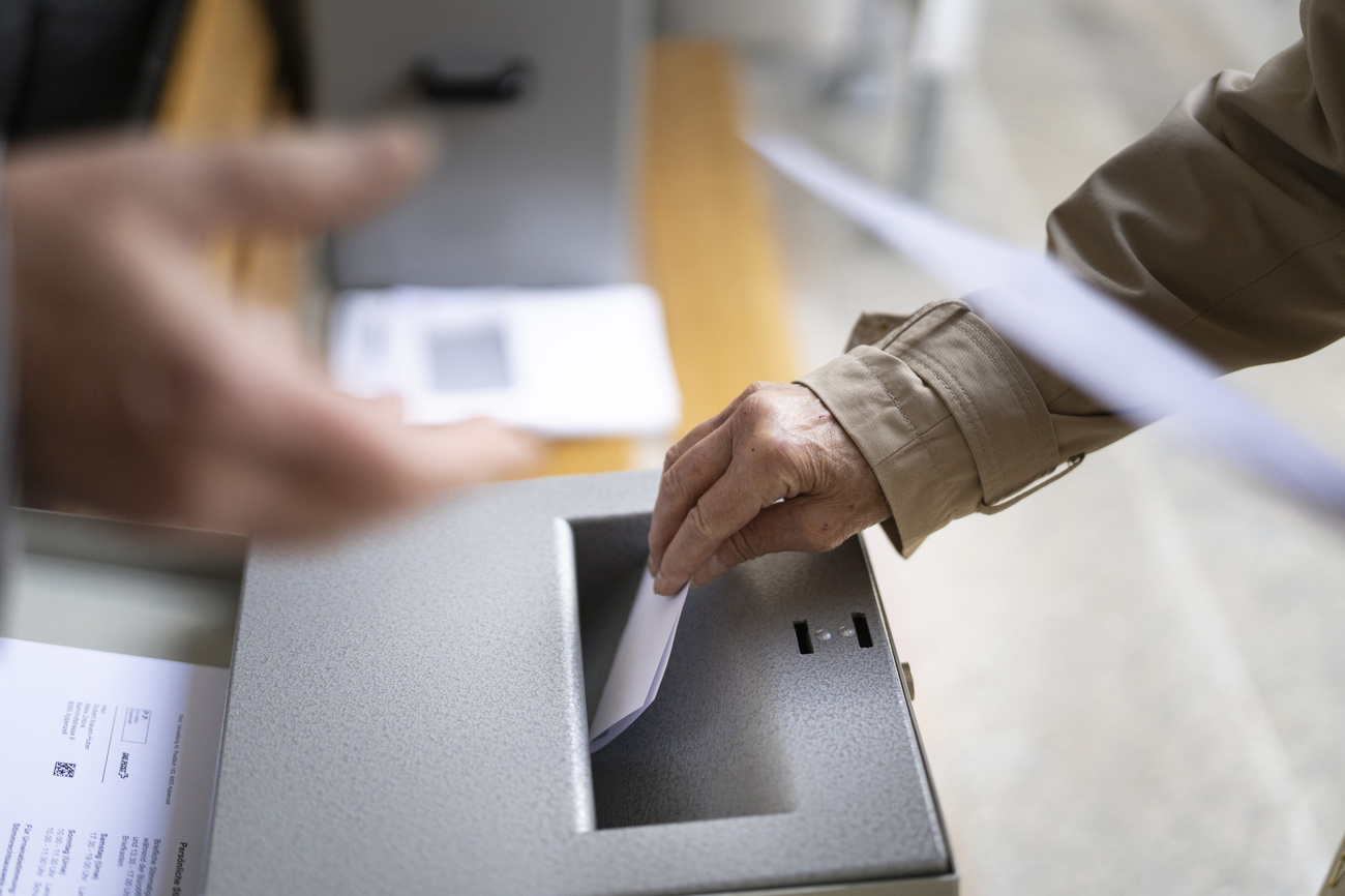 a man puts a ballot paper in the ballot box