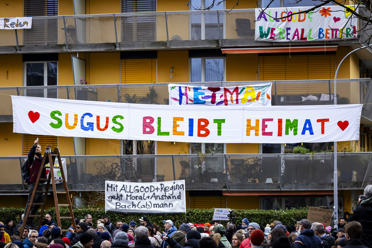 Der Protest gegen die Sugushäuser Anfang Dezember 2024. An einem der Häuser hängt ein Transparent, davor haben sich hunderte Menschen versammelt.