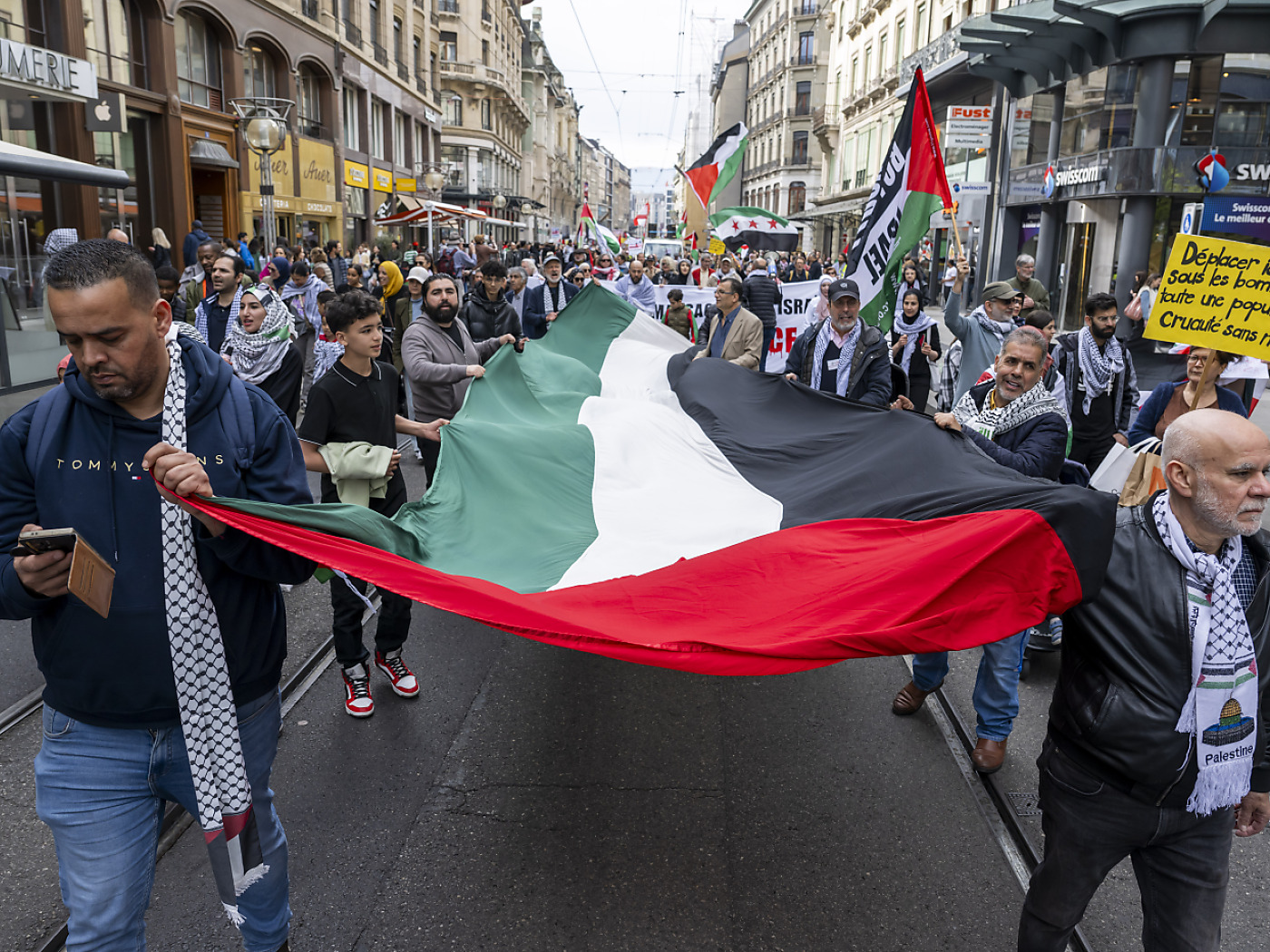 manifestanti reggono bandiera palestinese gigante