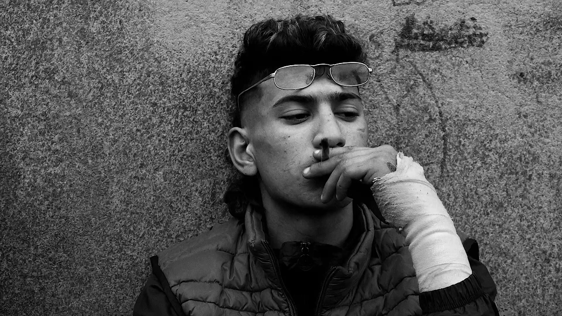 Un enfant fume contre un mur.