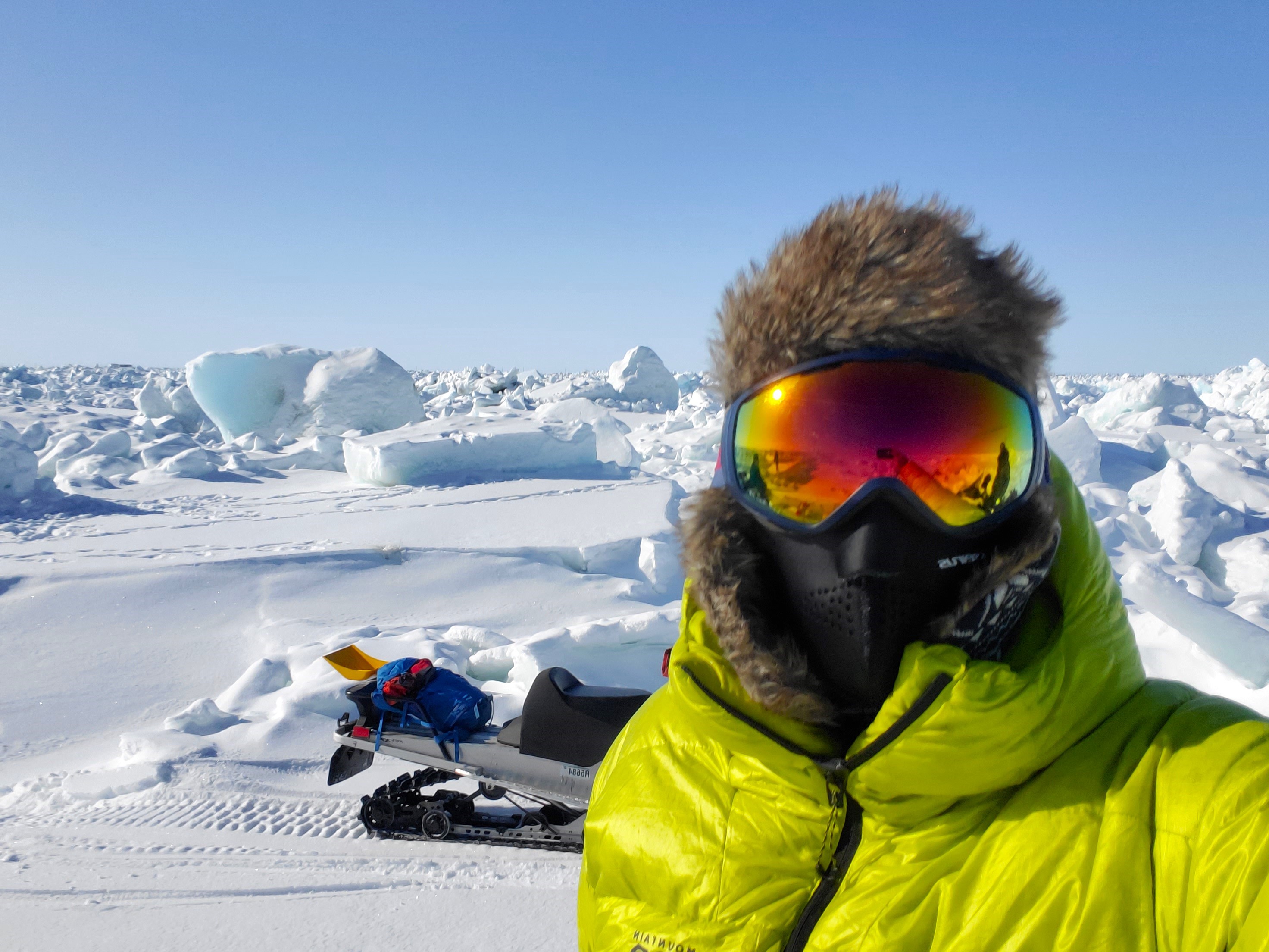Ein Mann, der wegen eisiger Kälte stark verhüllt ist und eine Skibrille trägt