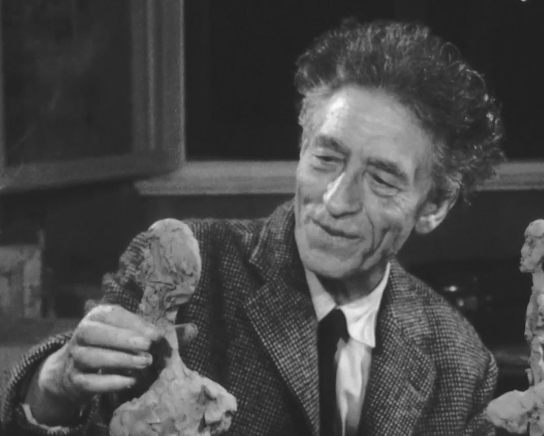 Alberto Giacometti con una sua scultura
