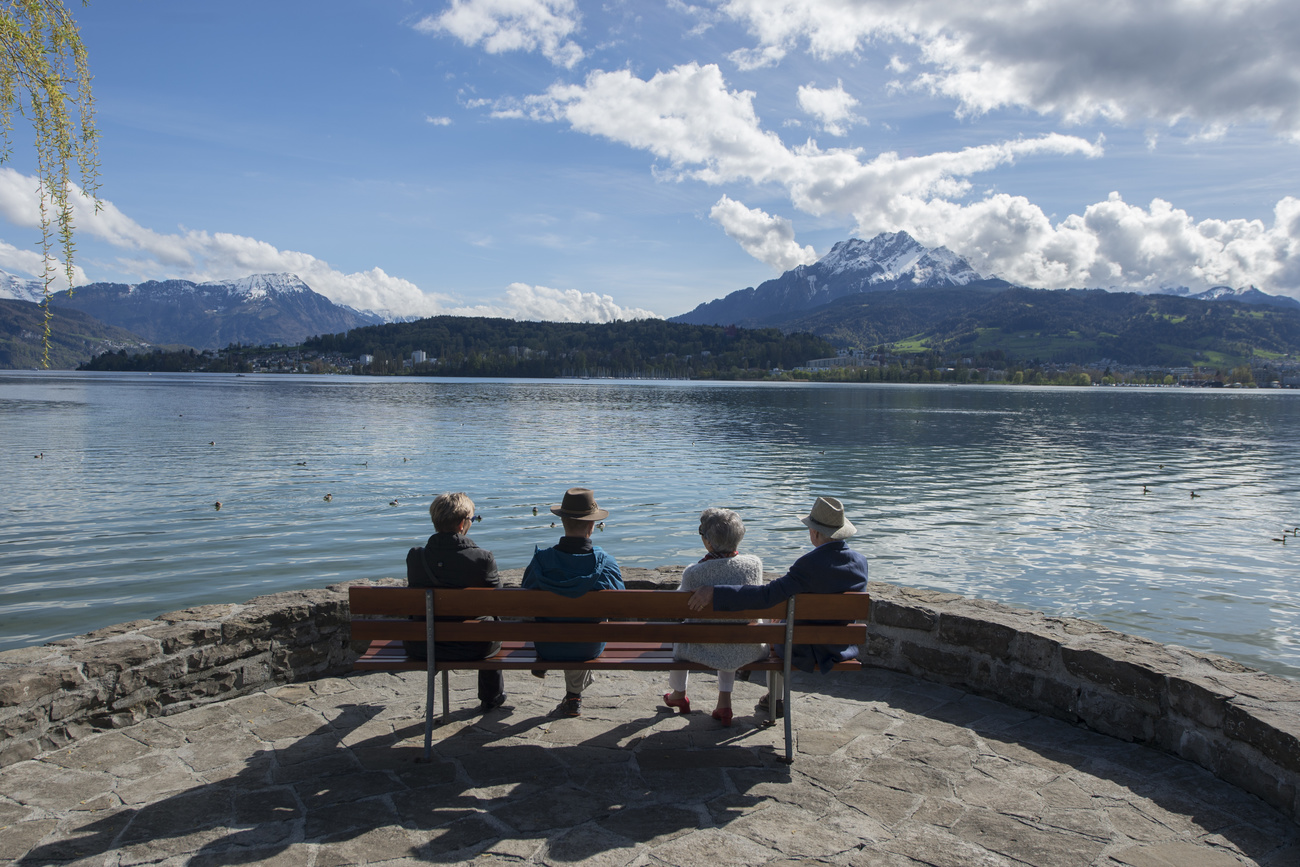 old people sitting on a bench by the lakeside