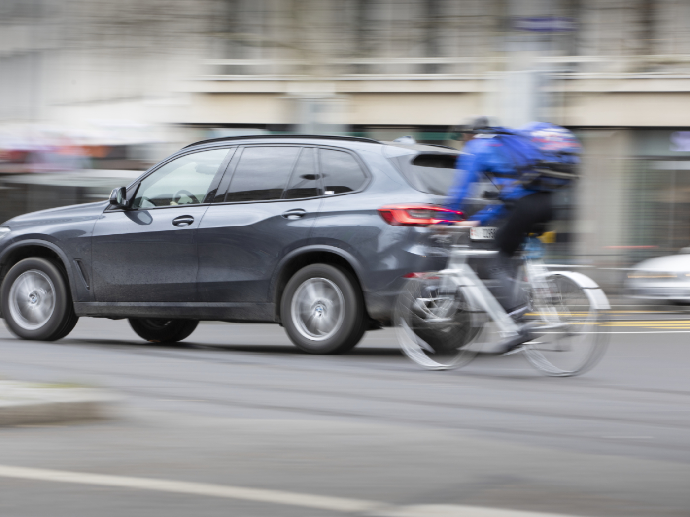 suv in strada accanto a un ciclista in bicicletta