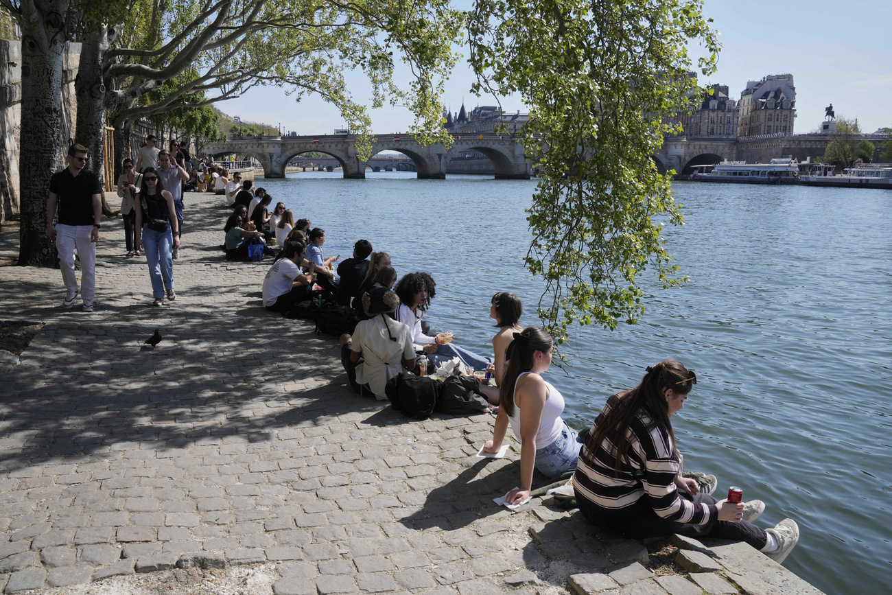 des gens assis en bord de Seine à Paris