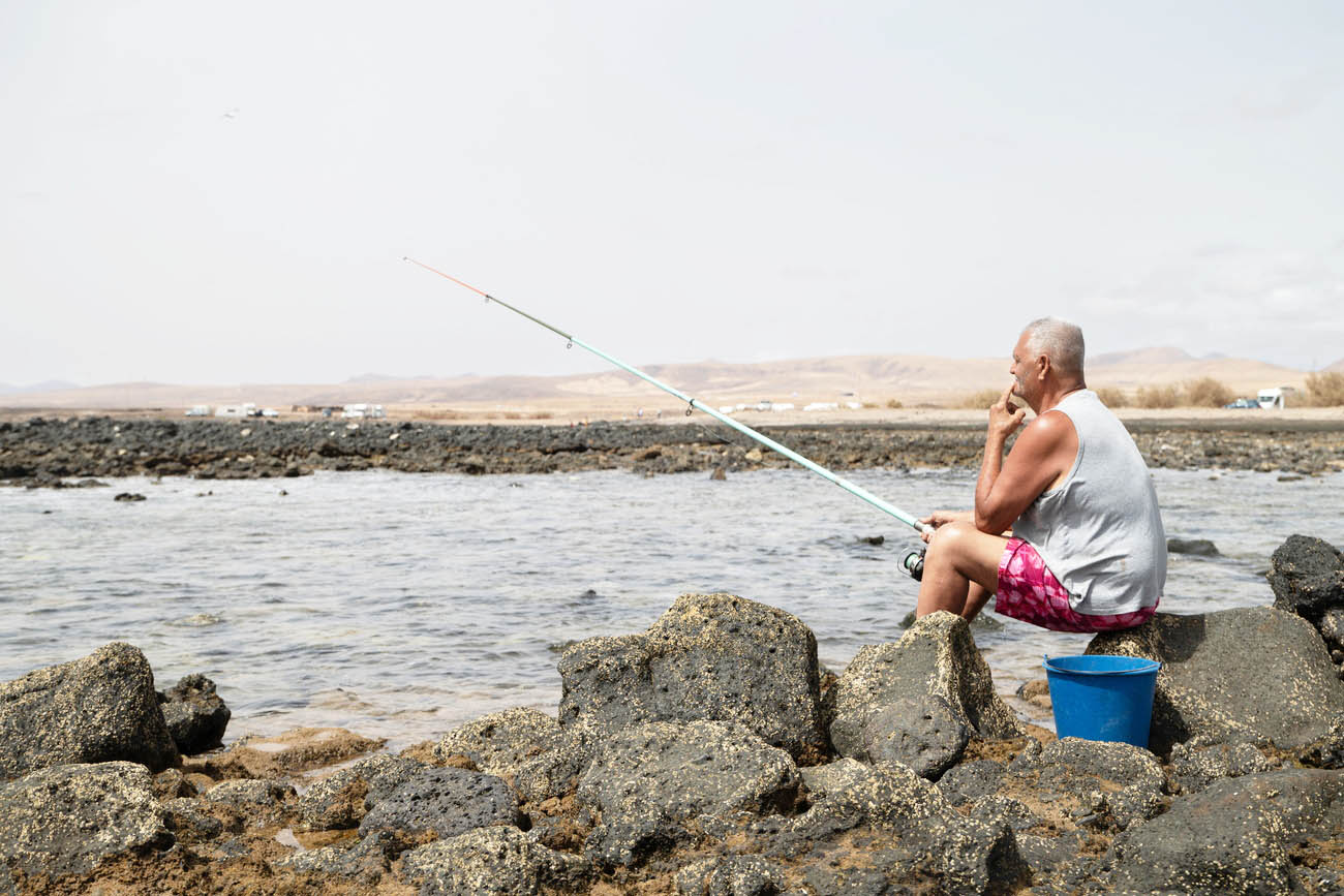 uomo anziano pesca in riva al mare