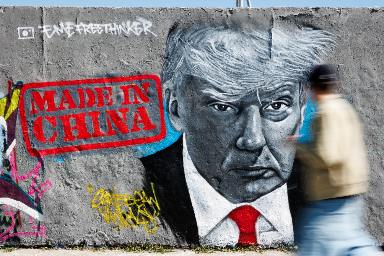 A passer-by walks in front of a graffito of Berlin-based artist Eme Freethinker that shows US President Donald J. Trump next to the writing 'Made in China' at the Mauerpark in Berlin, Germany, 28 April 2025. The United States of America and China are in a fight about tariff policies.