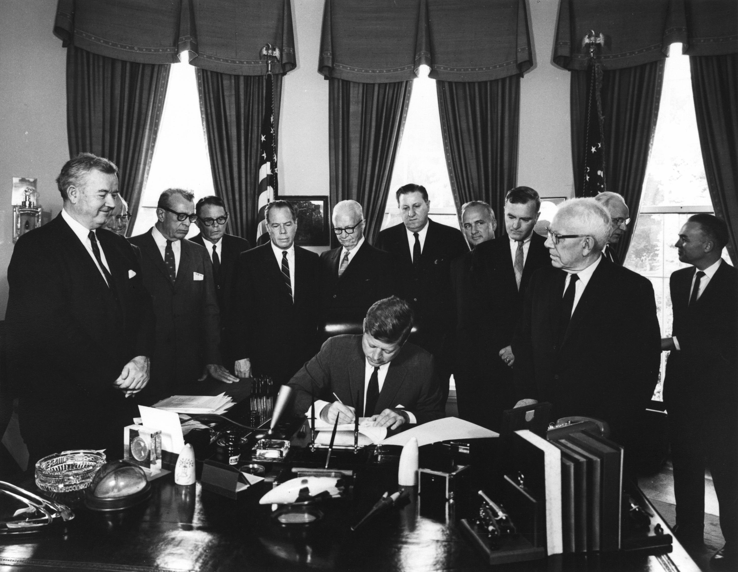 1961年11月3日、対外援助法に署名するジョン・F・ケネディ大統領(中央)。同月に設立された米国国際開発庁(USAID)の法的根拠となった