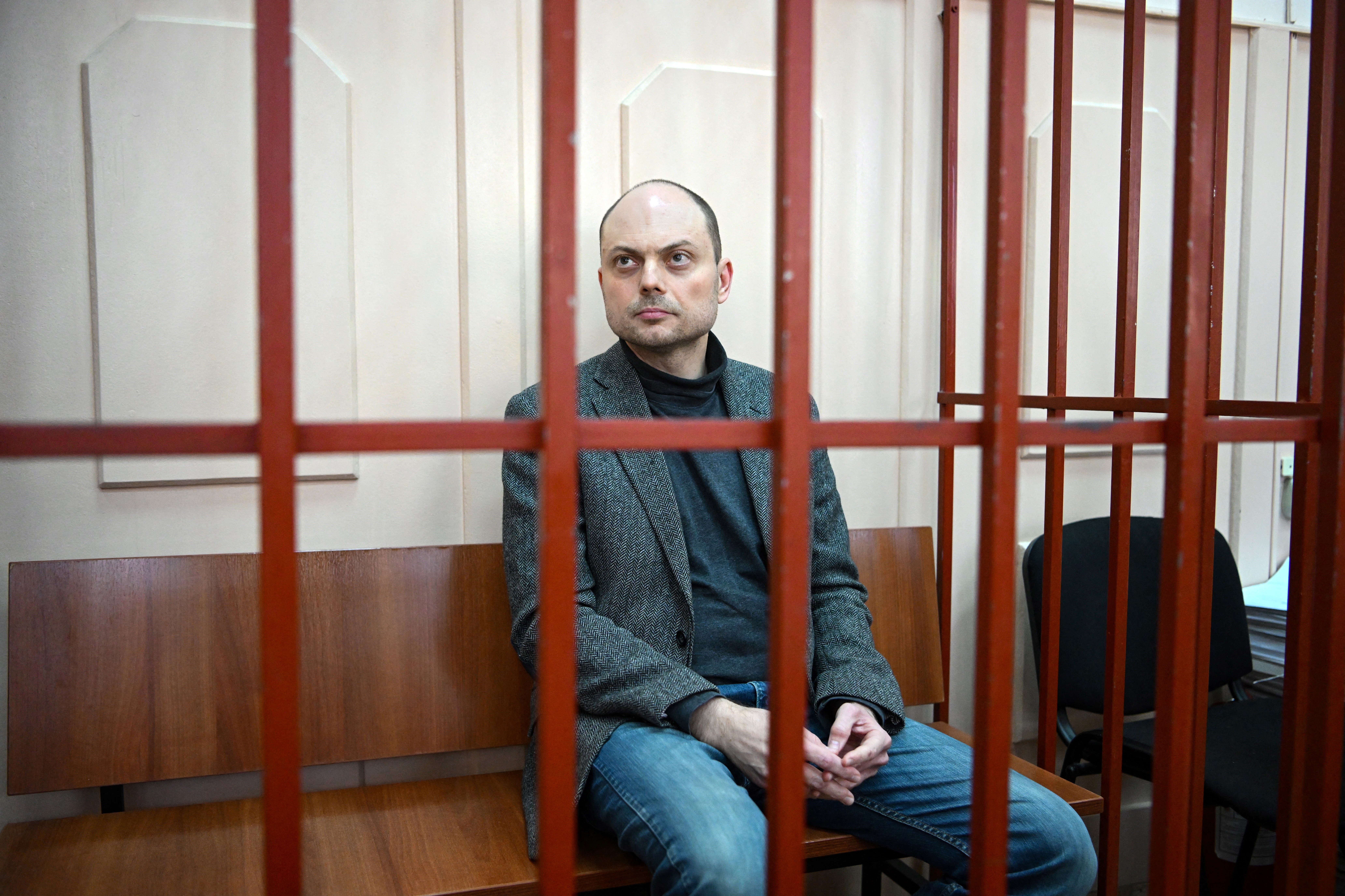 Vladimir Kara-Murza sits on a bench inside a defendants' cage during a hearing at the Basmanny court in Moscow on October 10, 2022.
