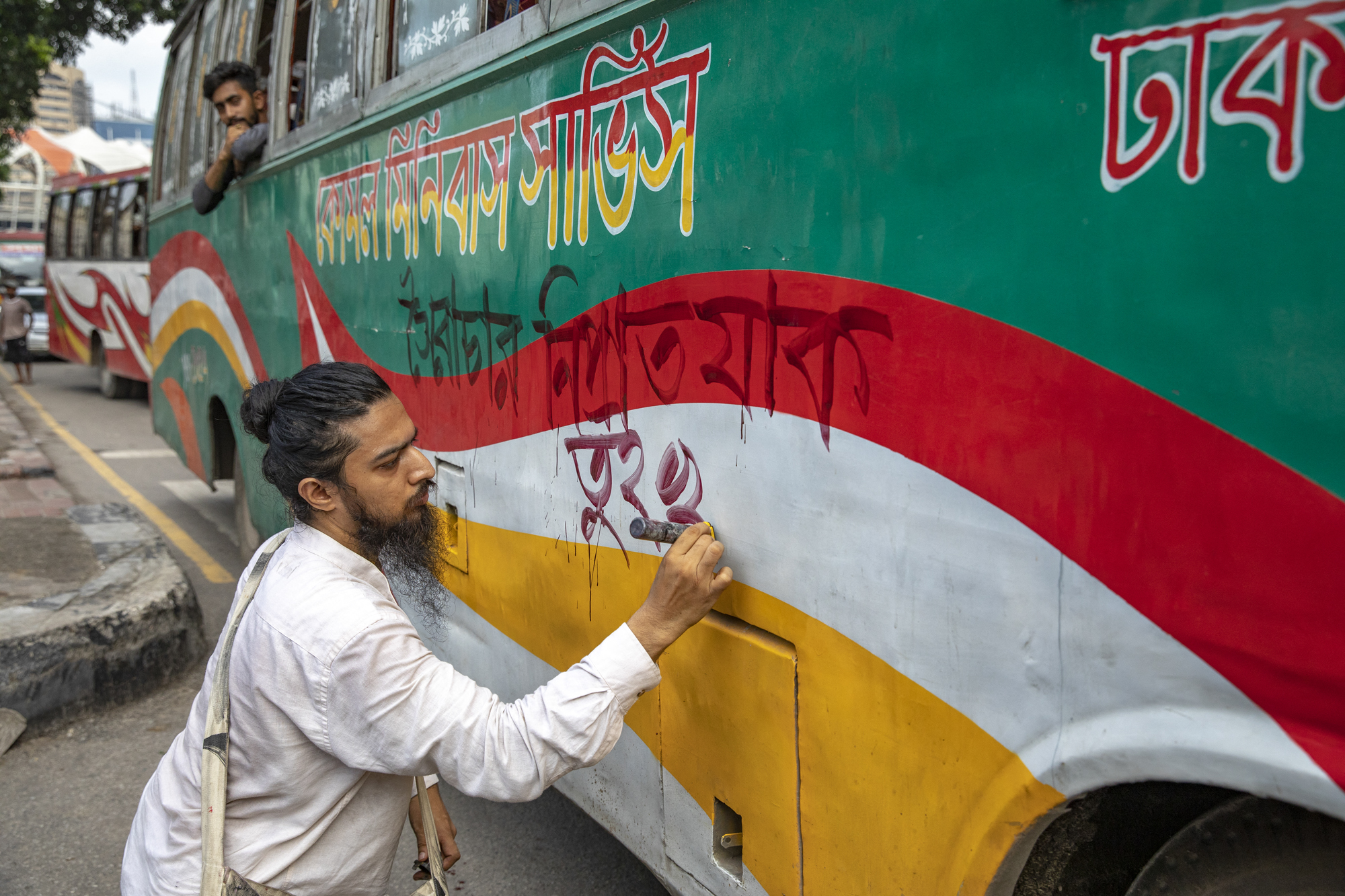 Cultural activists and members of civil society are painting on a local bus as they are staging a song march for victims who were killed during the recent nationwide student protests over quotas in government jobs, in Dhaka, Bangladesh, on July 30, 2024. (Photo by Ahmed Salahuddin/NurPhoto) (Photo by Ahmed Salahuddin / NurPhoto / NurPhoto via AFP)