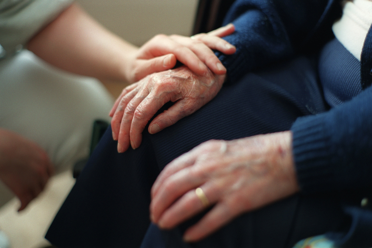 assistete di cura appoggia mano su mano di persona anziana