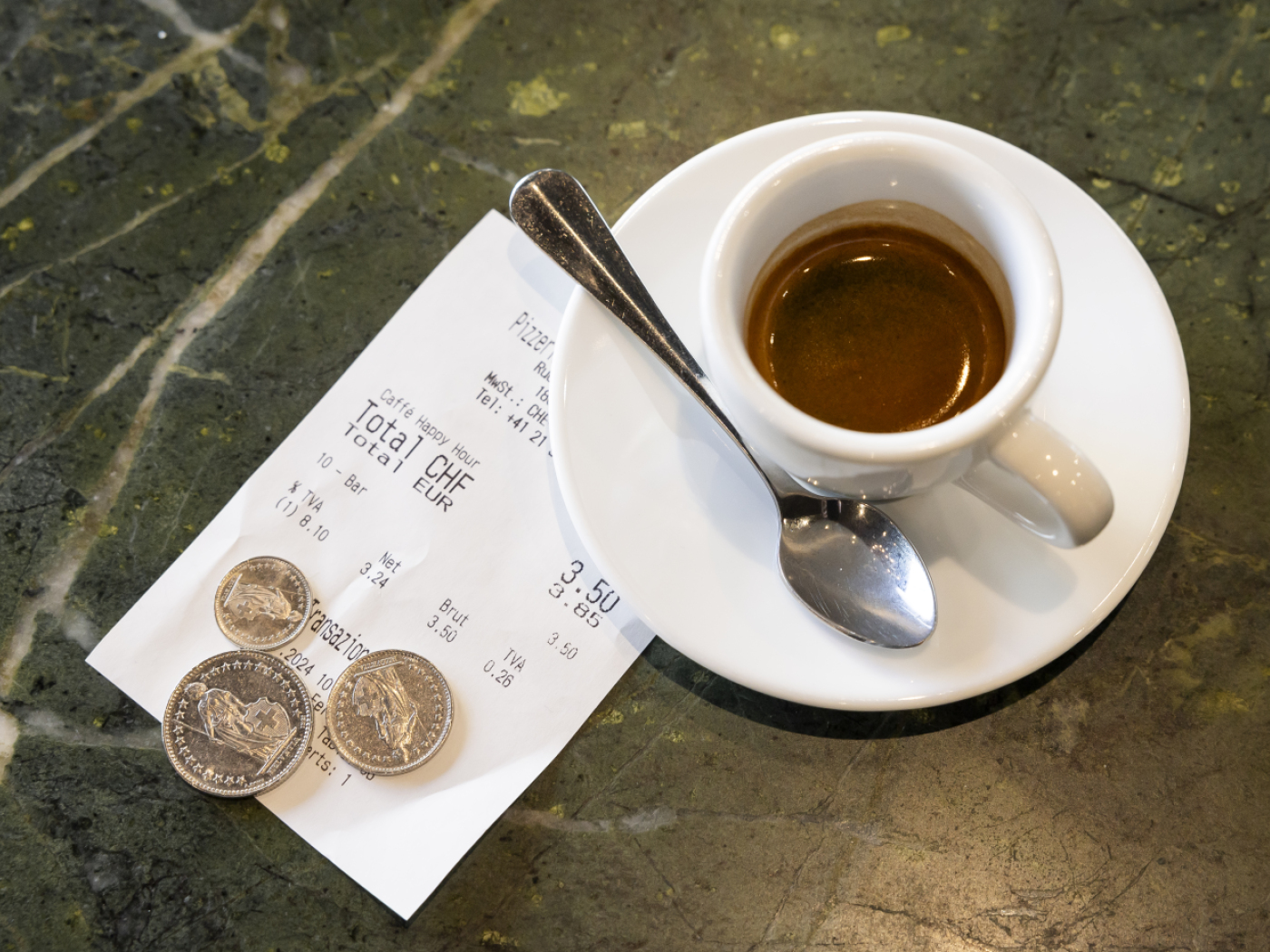 tazzina di caffé con conto e monete appoggiate sul conto