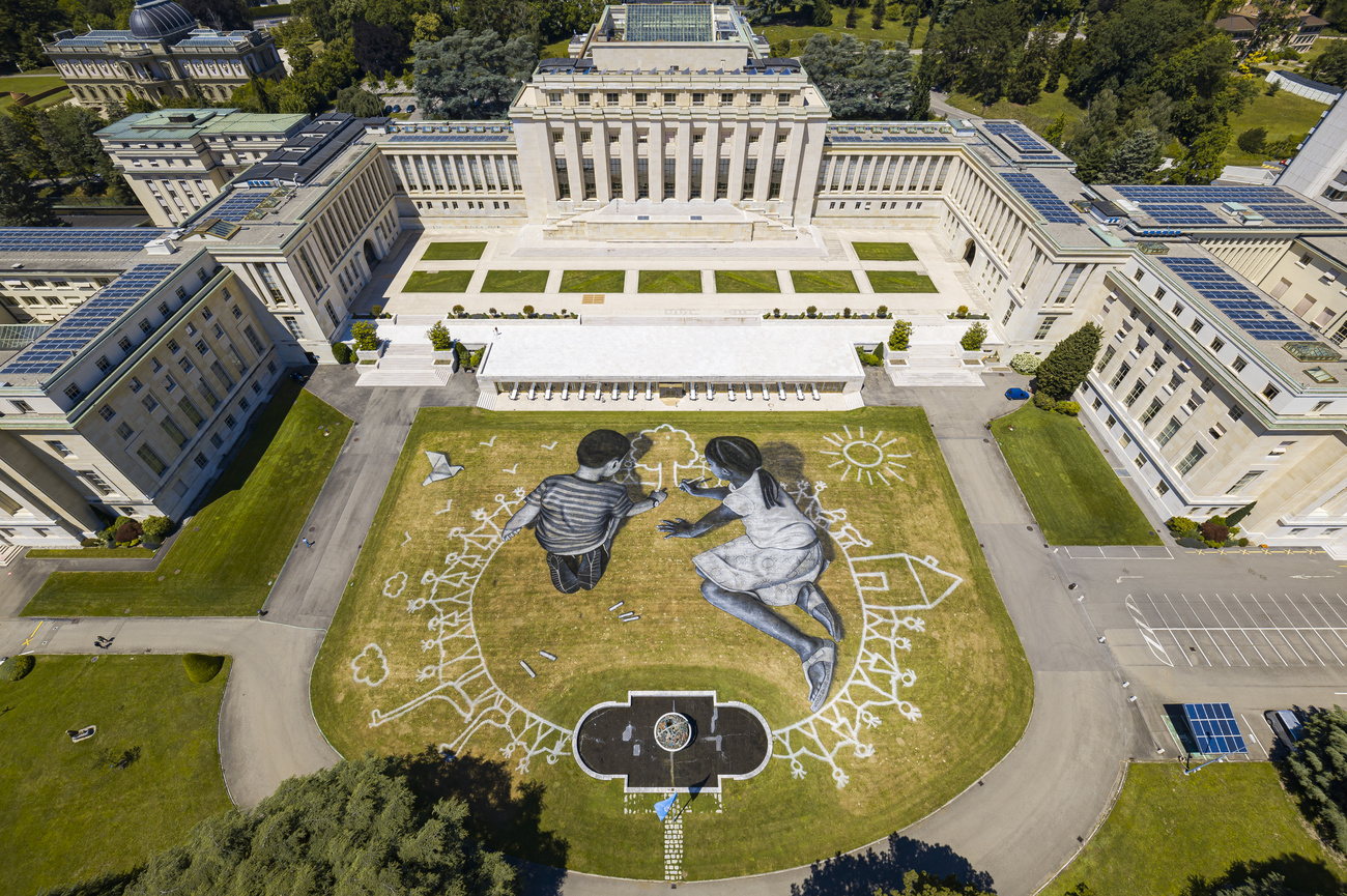 Luftaufnahme eines Freskos auf dem Rasen vor dem Palais des Nations in Genf, das zwei Kinder beim Zeichnen zeigt