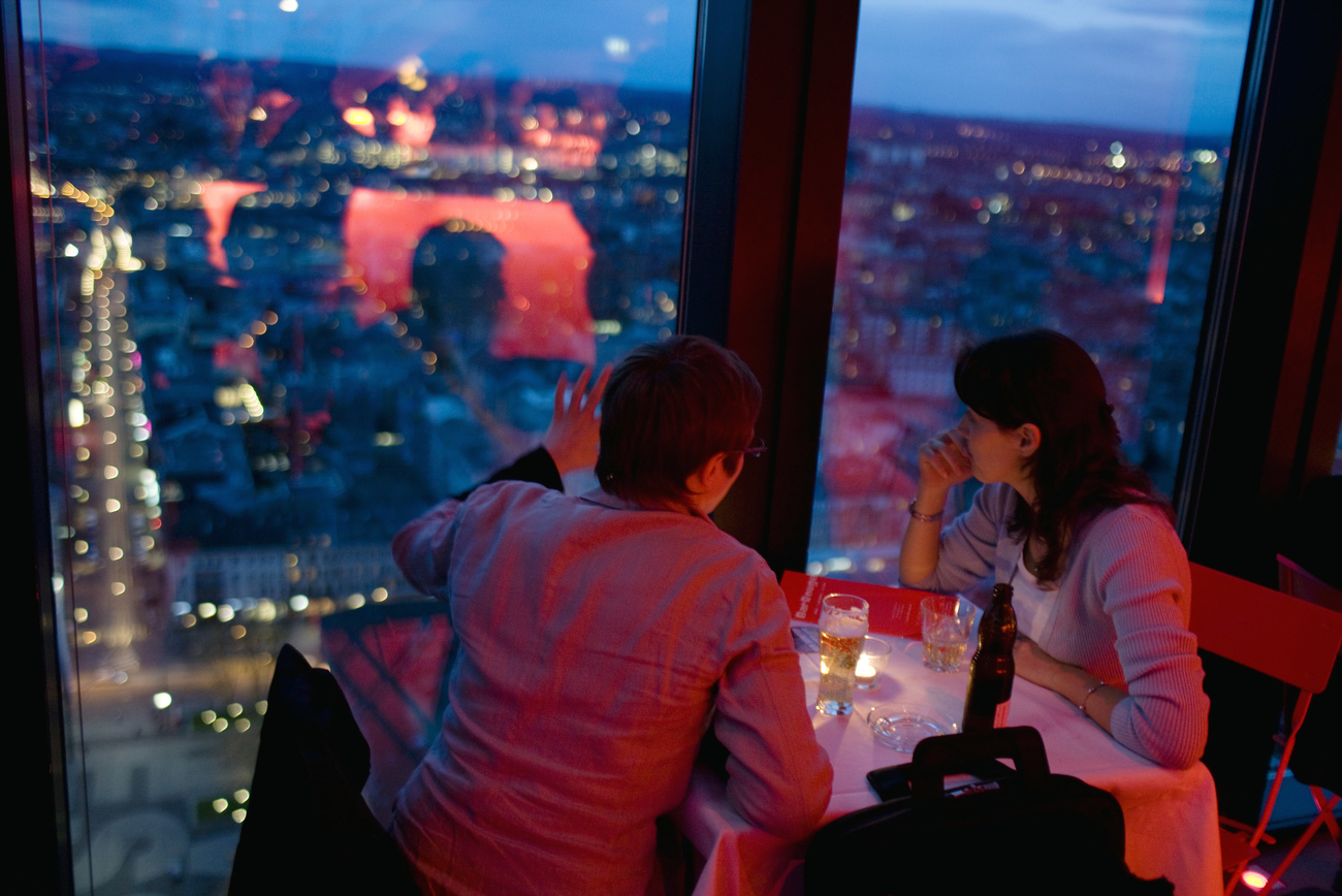 A couple look down on the city of Basel from a bar.