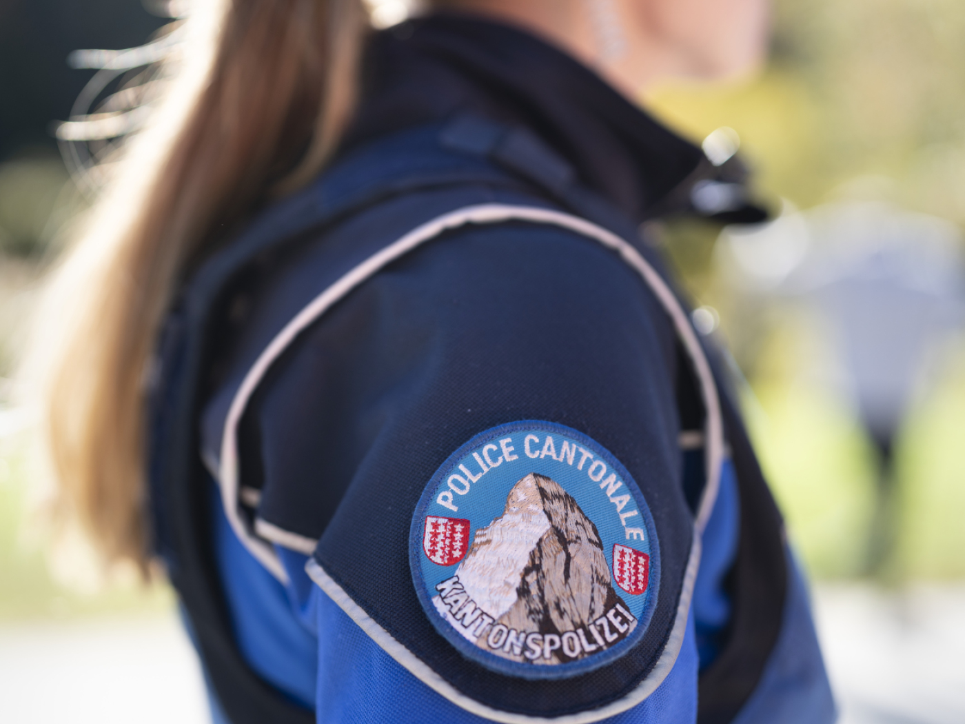 logo polizia cantonale vallesana sulla manica di una divisa indossata da una donna