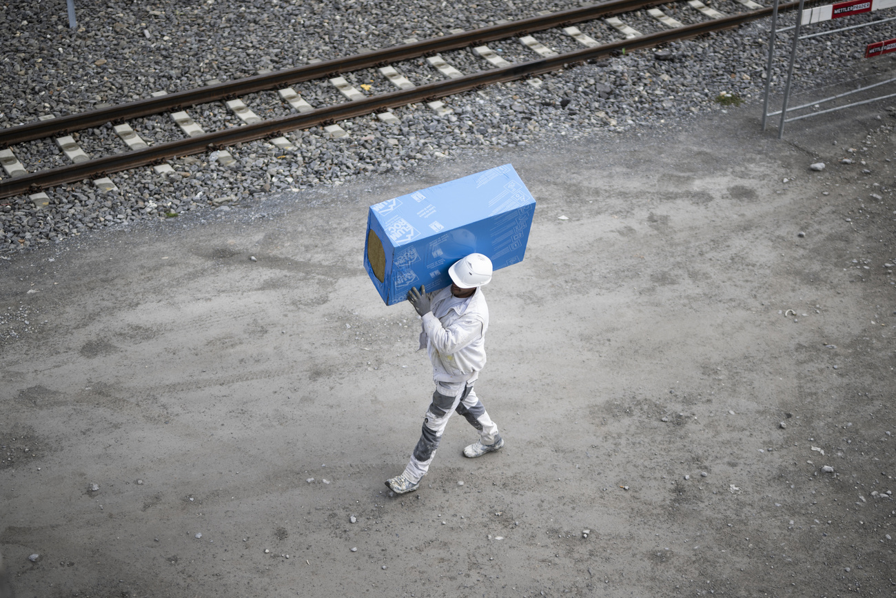 operaio vestito di bianco trasporta uno scatolone azzurro