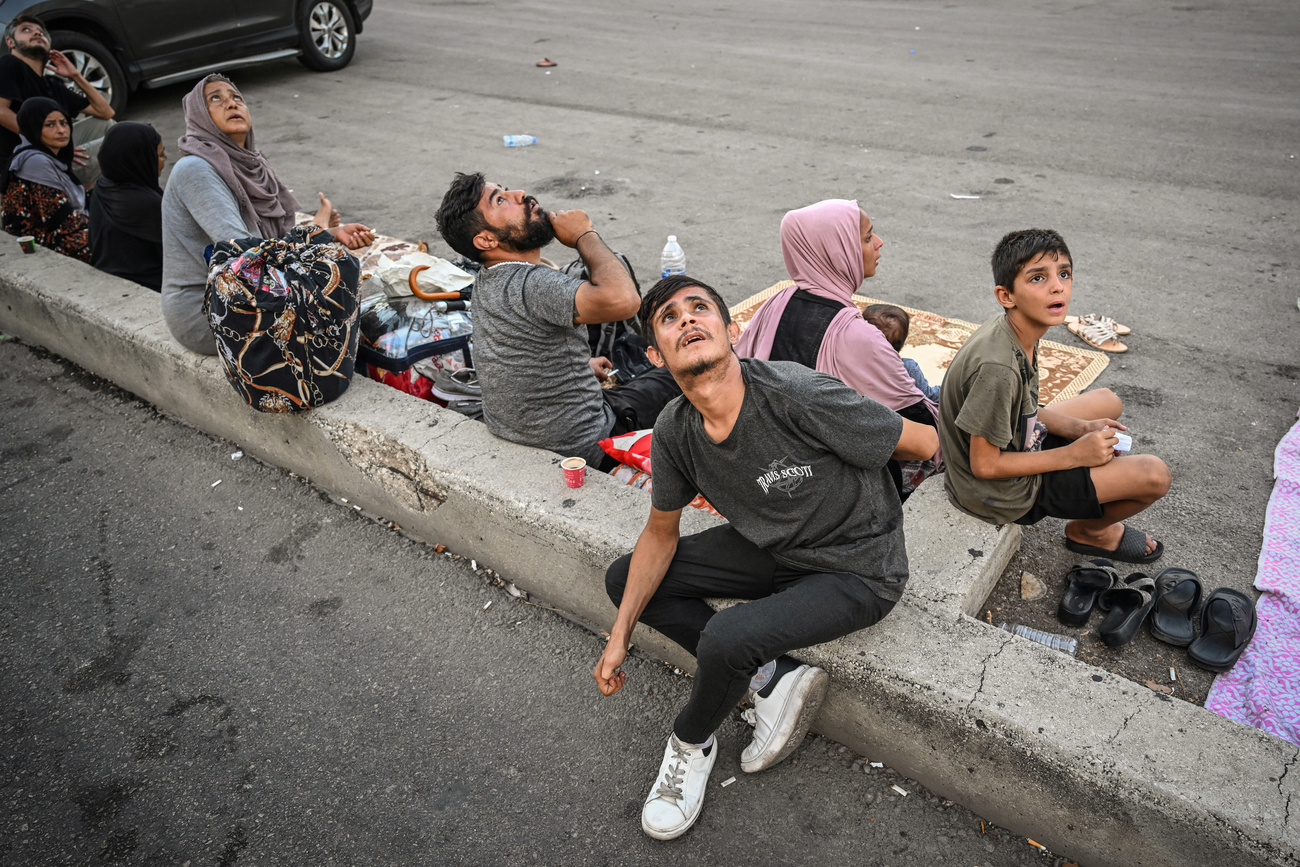 Des personnes lèvent anxieusement les yeux vers le ciel lors d’une frappe de drone israélien, alors qu’elles se mettent à l’abri loin des bâtiments dans le quartier de Dahiyeh à Beyrouth.