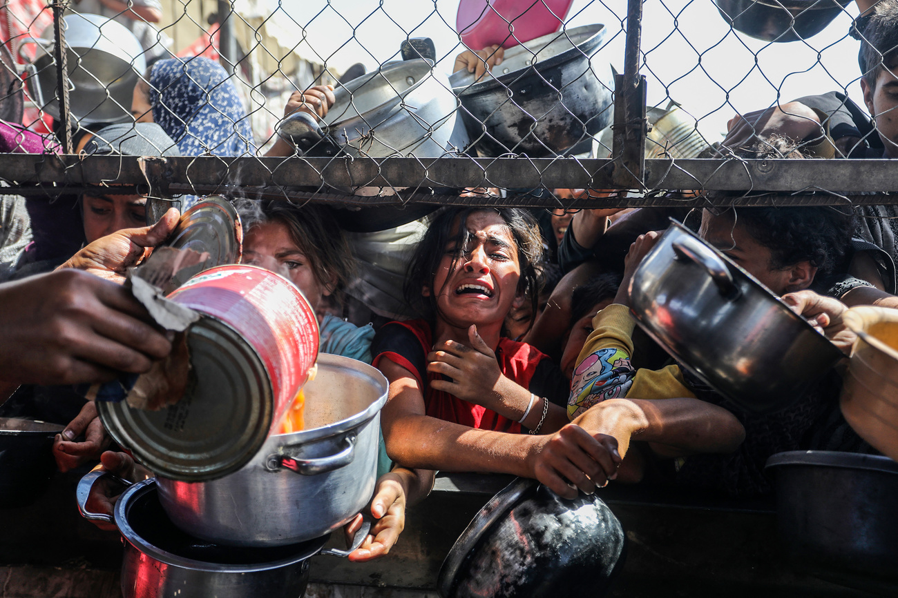 Palestinian girls crowd to receive food portions from a charity kitchen in a refugee camp in Khan Younis, southern Gaza Strip, on Friday, May 30, 2025.