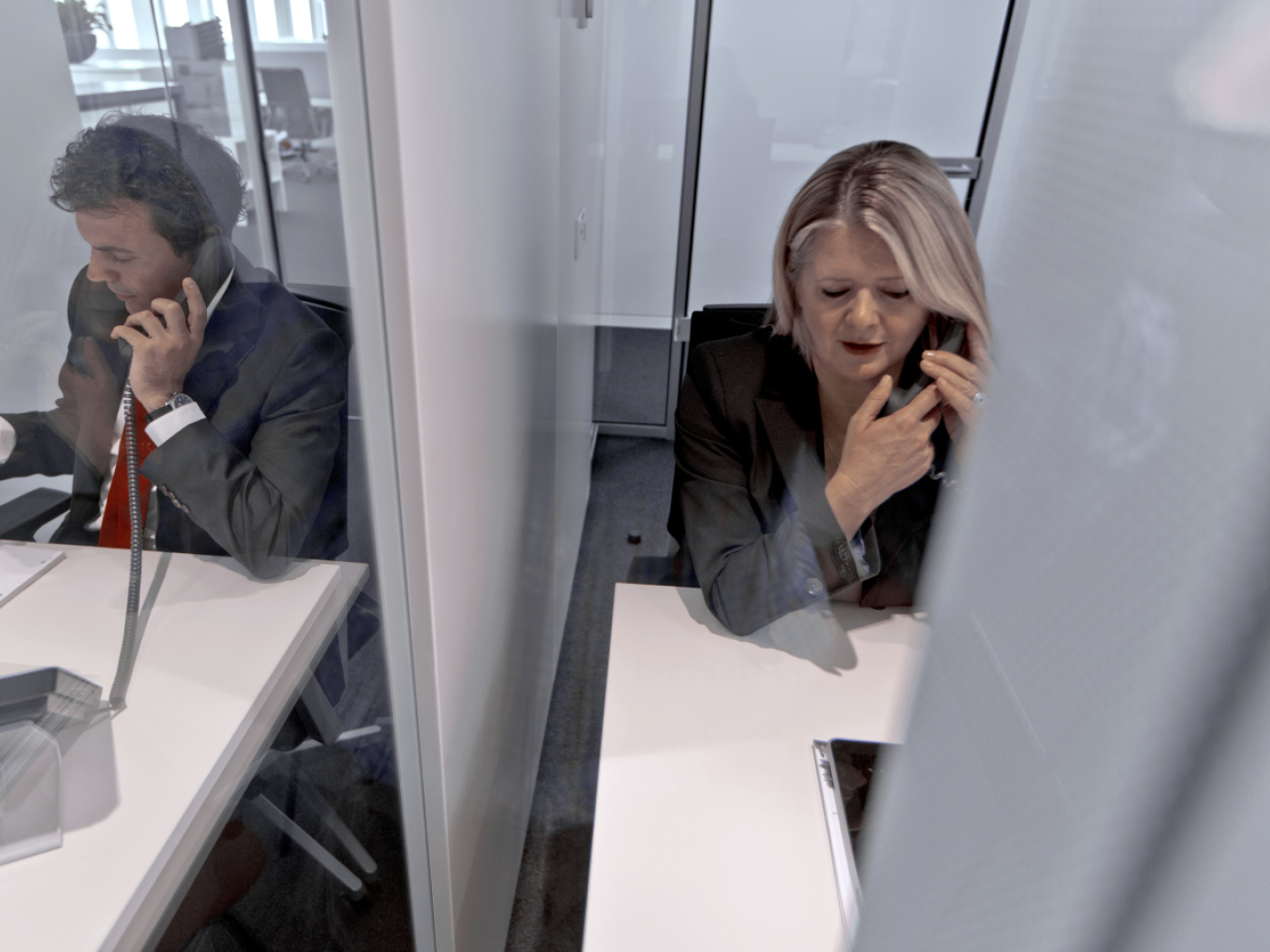 due persone al telefono in due cubicoli