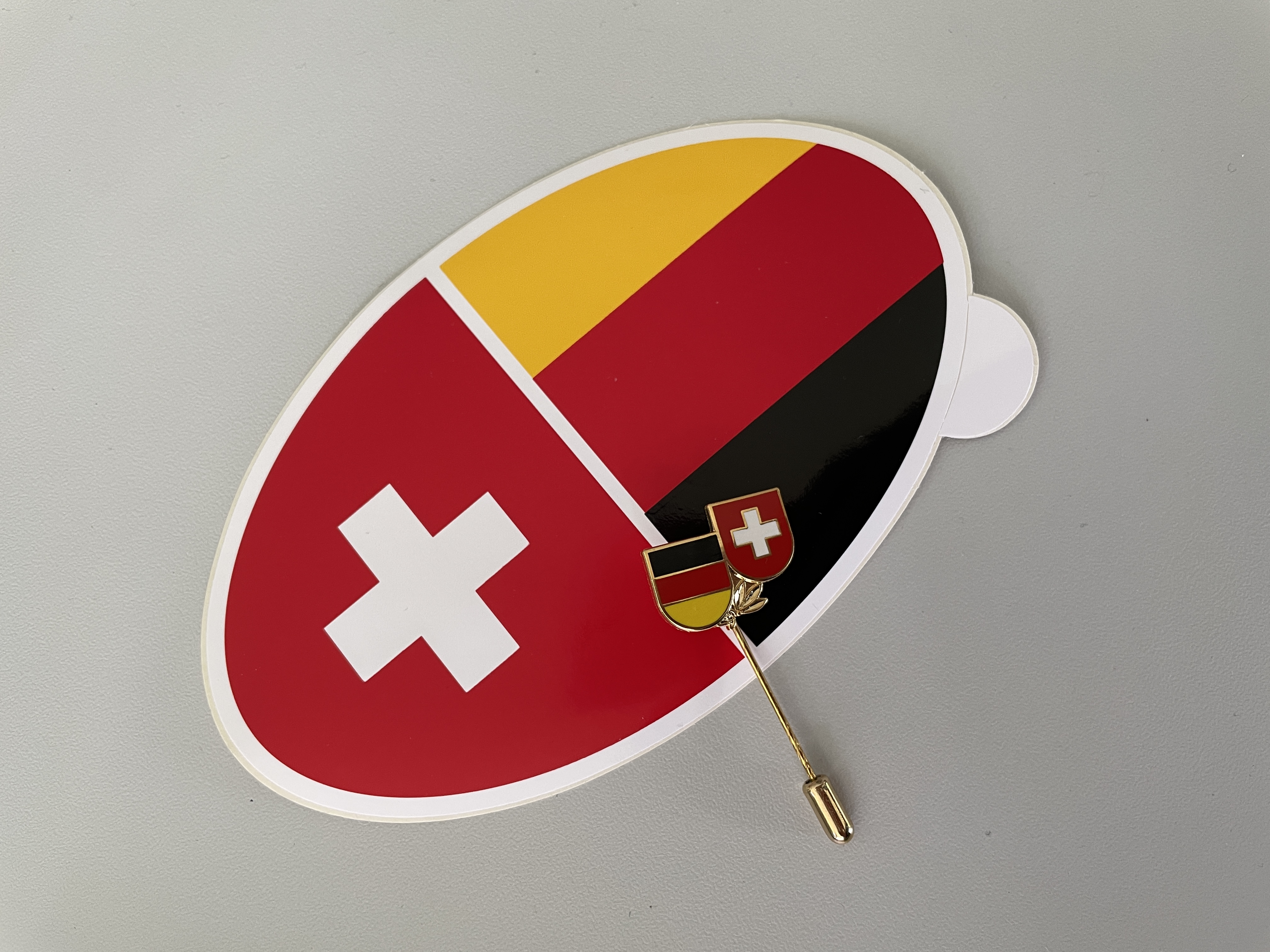 Schweizer und deutsches Wappen auf einem Pin und Sticker