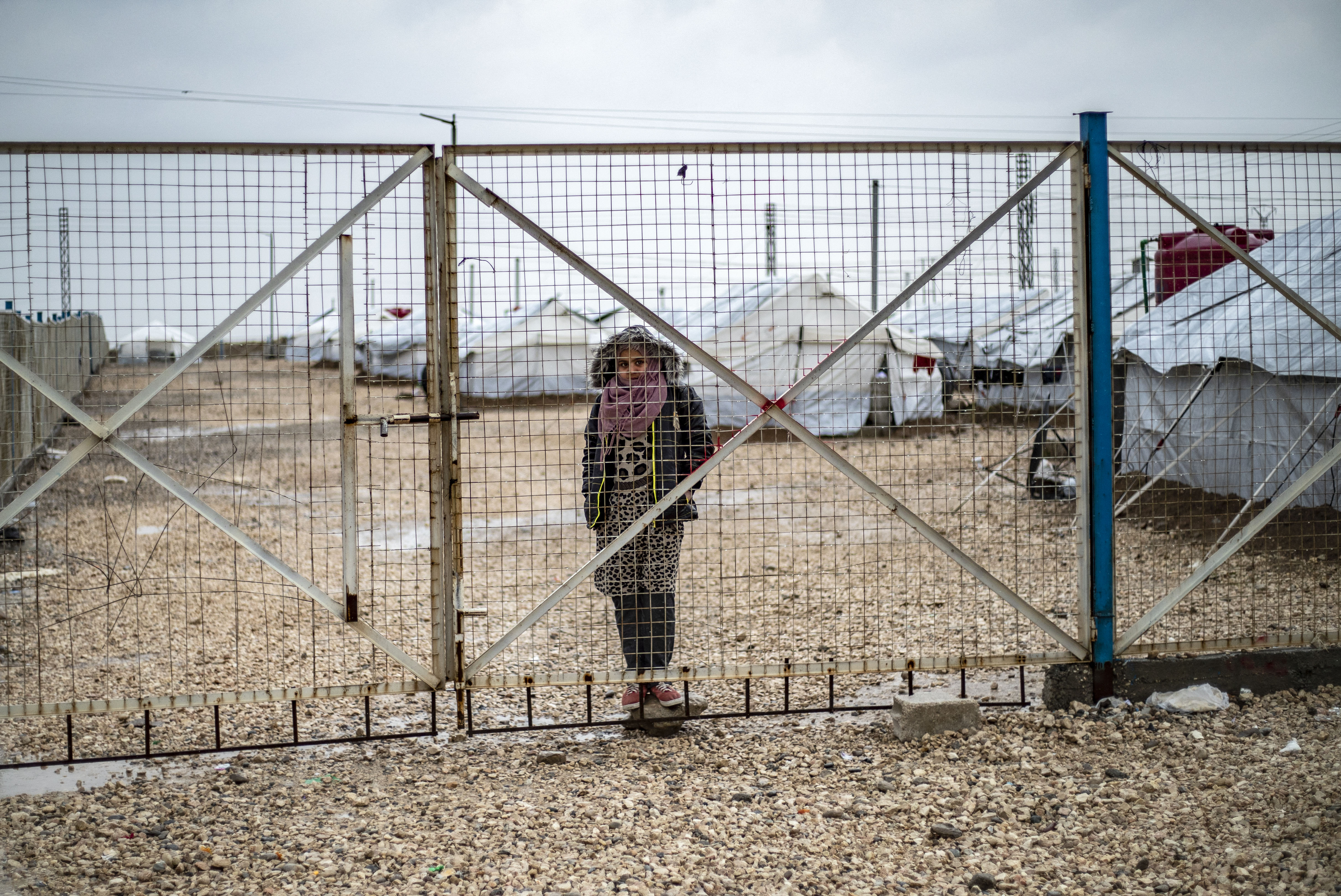 Jeune fille derrière le grillage d'un camp en Syrie.